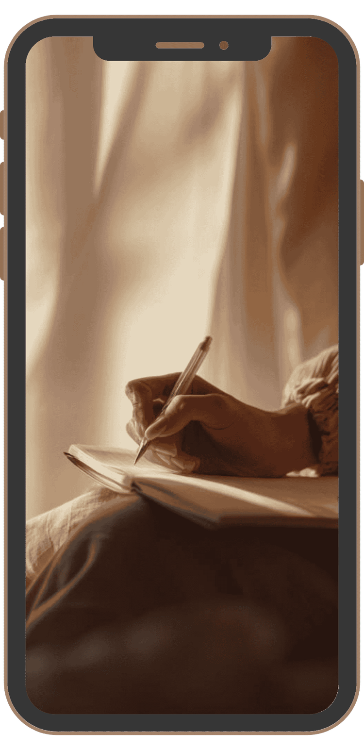 A person writing in a notebook on a smartphone screen with warm lighting.