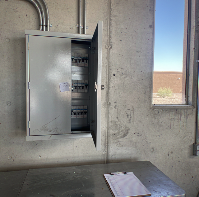 Industrial electrician inspecting electrical panel with safety gloves
