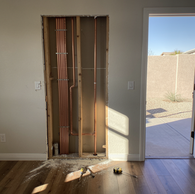 Electrician rewiring exposed cables in open residential wall