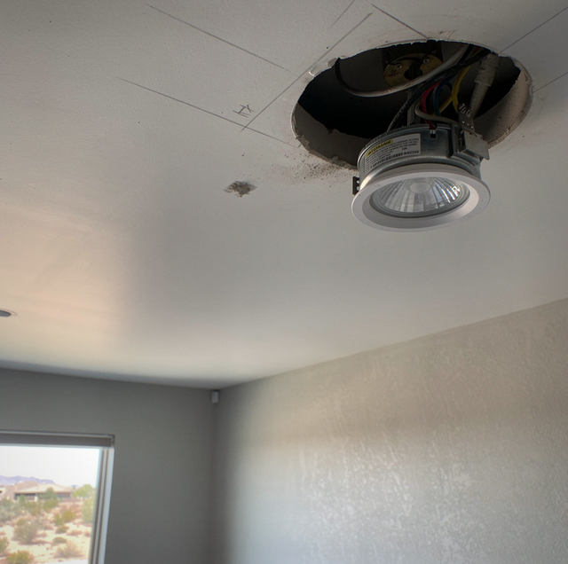 electrician wiring ceiling light fixture during home renovation