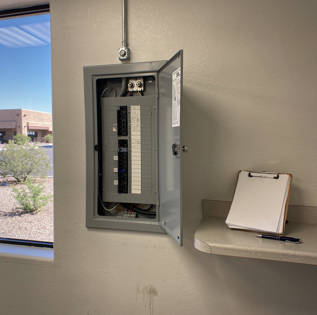electrician testing commercial fuse board with multimeter