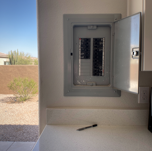 electrician testing breaker panel with multimeter