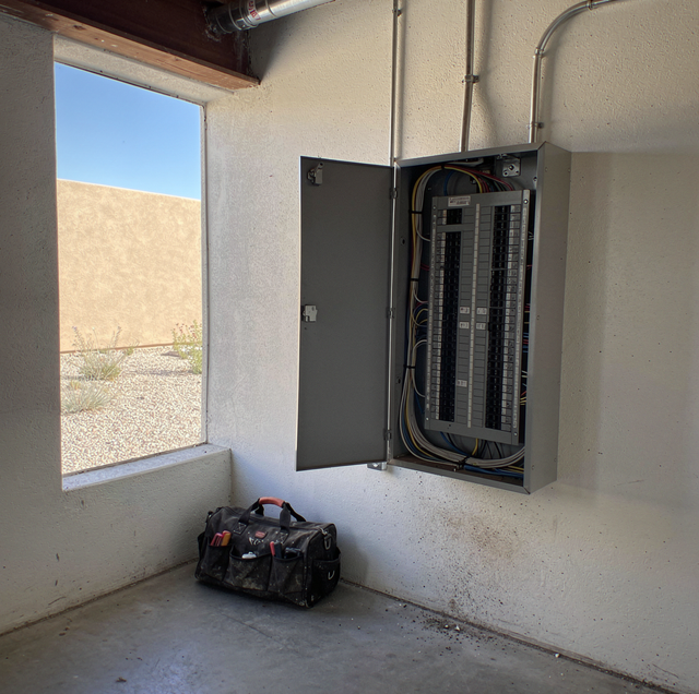 electrician testing commercial breaker panel with multimeter