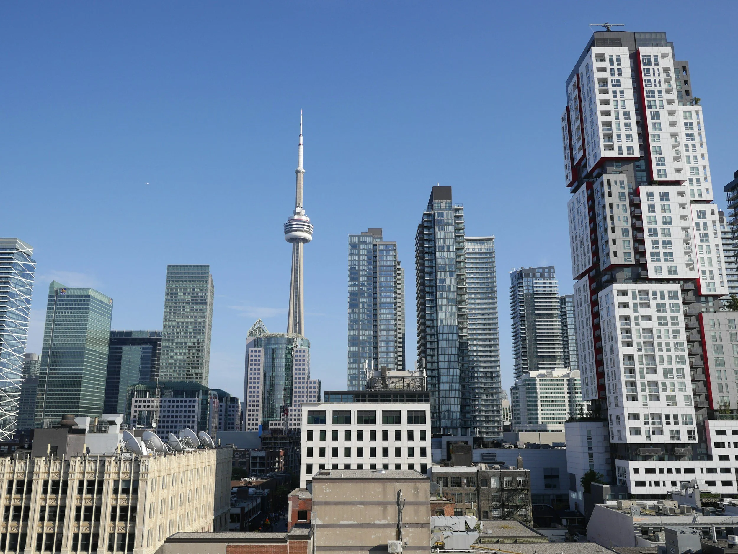 City skyline featuring tall modern buildings, including the CN Tower, against a clear blue sky.