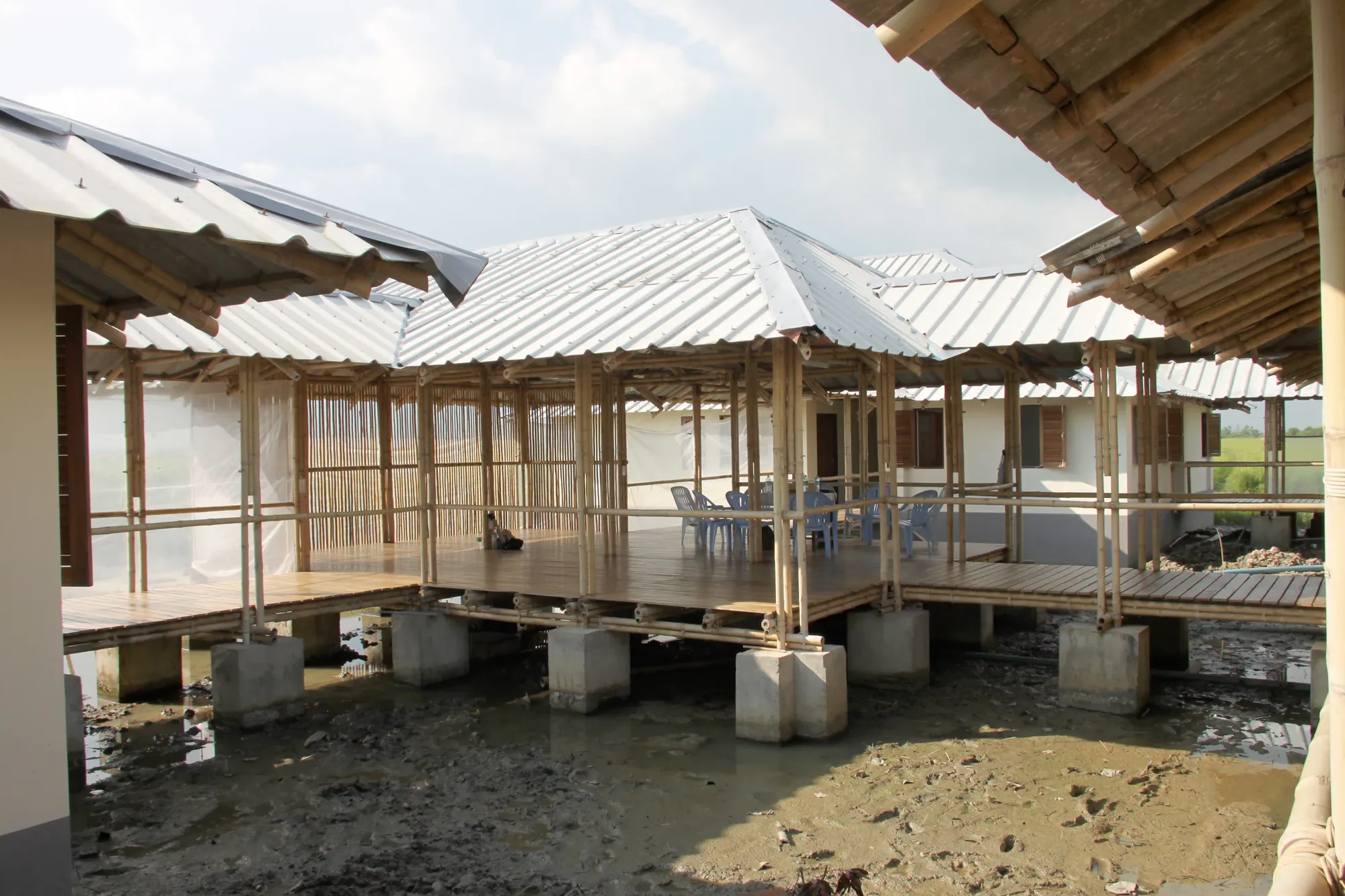 Ein Bauprojekt zeigt eine hölzerne Terrasse unter einem Dach, mit Sitzgelegenheiten und offenen Wänden, während das Gebäude im Bau ist.