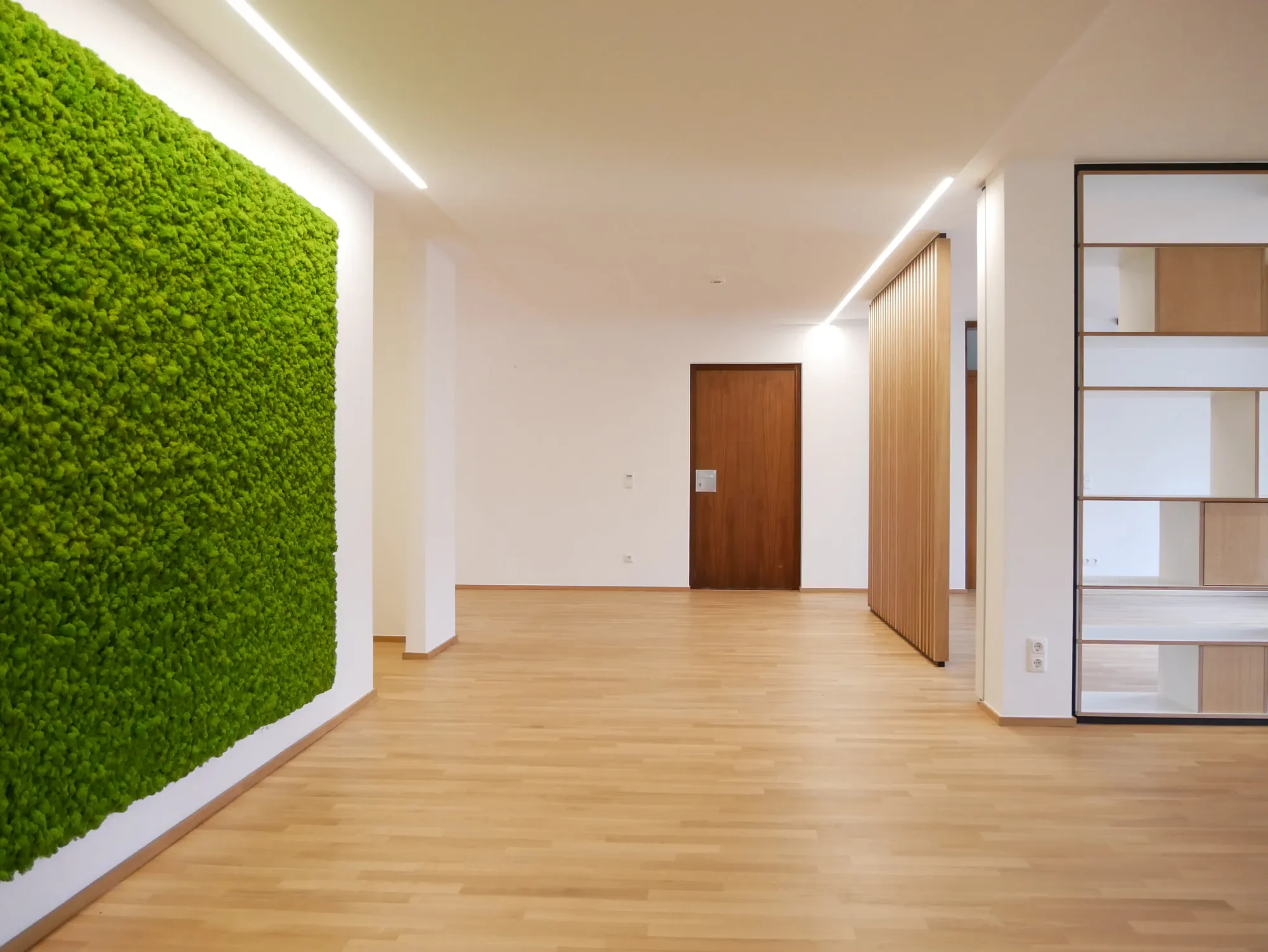 Moderner Innenraum mit Holzfußboden, weißen Wänden und einer grünen Mooswand.