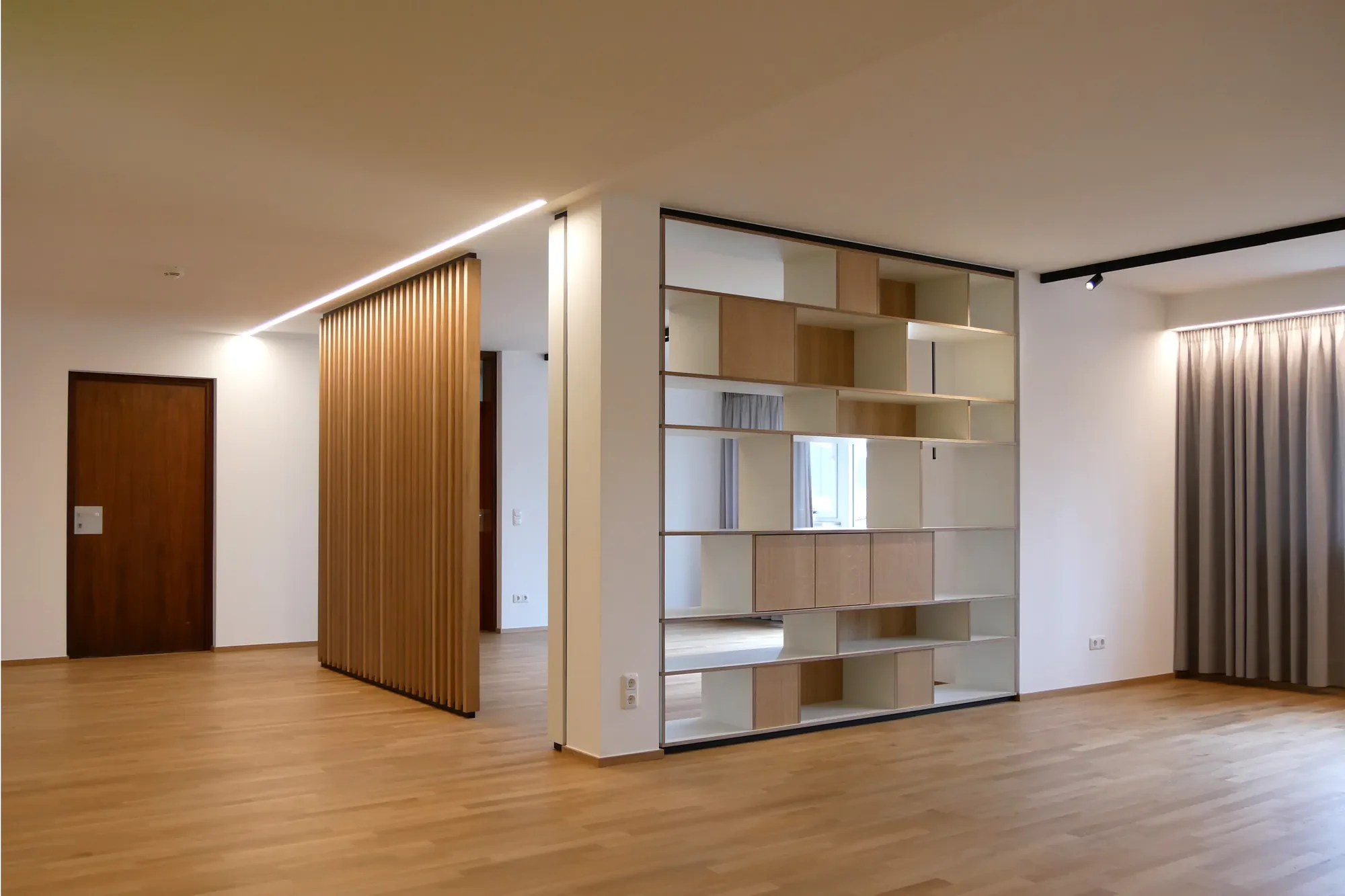 Moderner, offener Wohnraum mit Holzboden, einer offenen Raumteilung aus Regal, einer Holzlamellenwand, Vorhängen und viel natürlichem Licht.