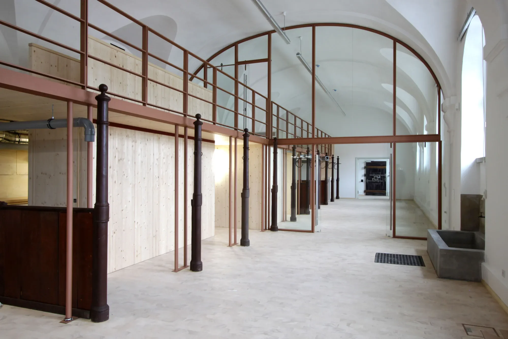 Innenansicht eines modernen Gebäudes mit hohem, gewölbtem Decken und großen Fenstern, offene Raumaufteilung mit Holz- und Metallstrukturen