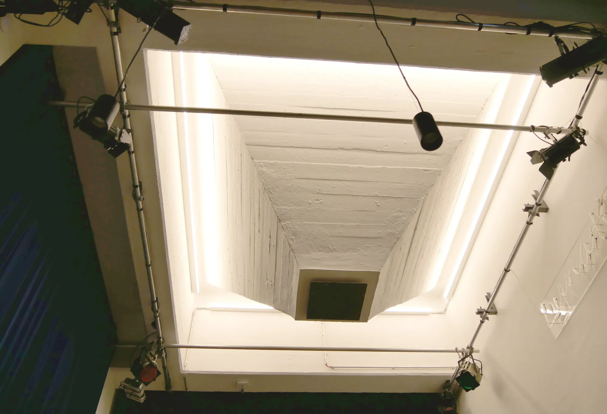 Fotografie eines Kinos mit Projektionsleinwand, umgeben von technischer Ausrüstung und Beleuchtungseinrichtungen. Offenbar eine Aufnahme eines Filmvorführungsraums.