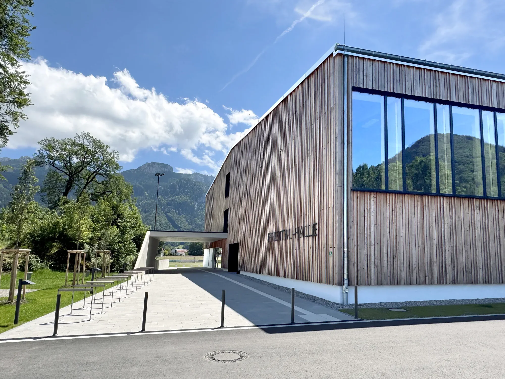 Modernes Holzgebäude mit großen Glasfassaden vor einer Bergkulisse, auf dem Gebäude steht 'FUNKTAL-HALLE'