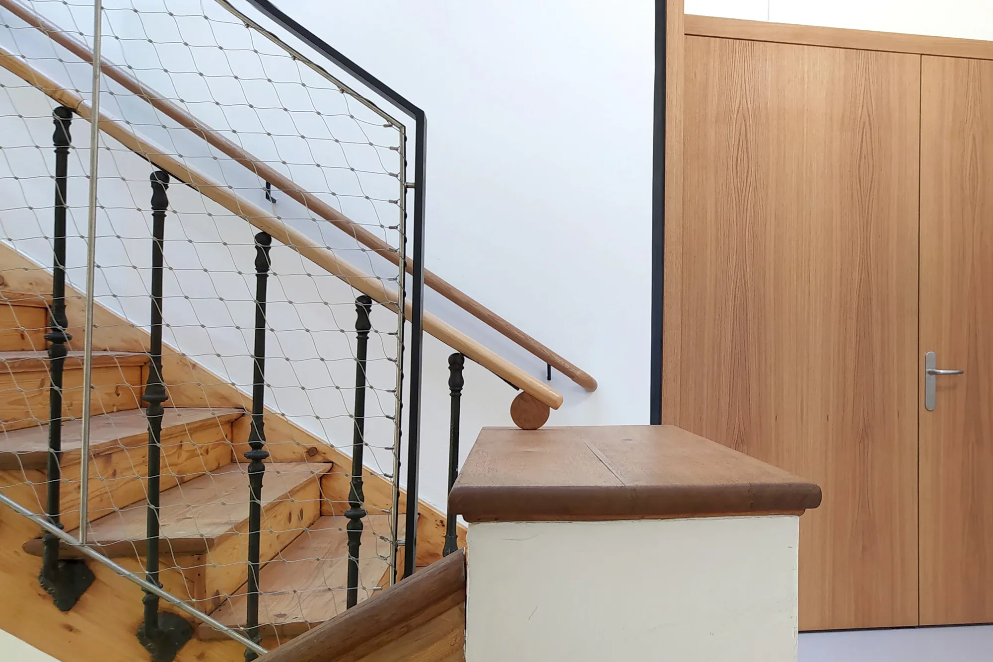 Innenaufnahme eines Hauses mit Treppe aus Holz und eine Holztür an der Wand.