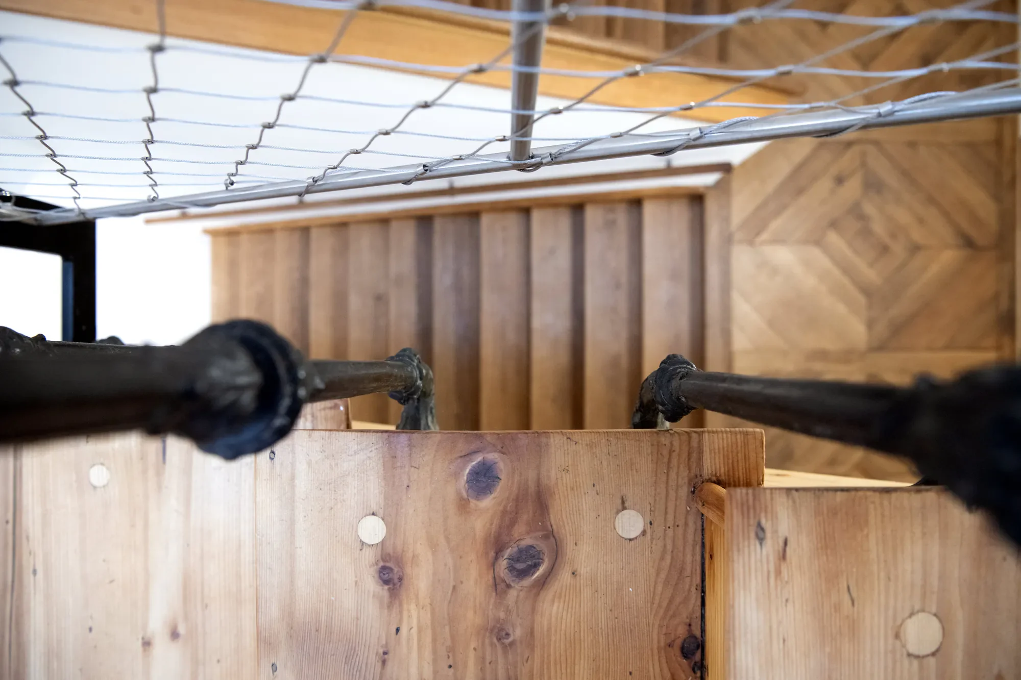 Blick von oben auf eine Holztreppe mit verstecktem Boden, geländer aus schwarzem Metall und eine Wand mit Holzverkleidung im Hintergrund.