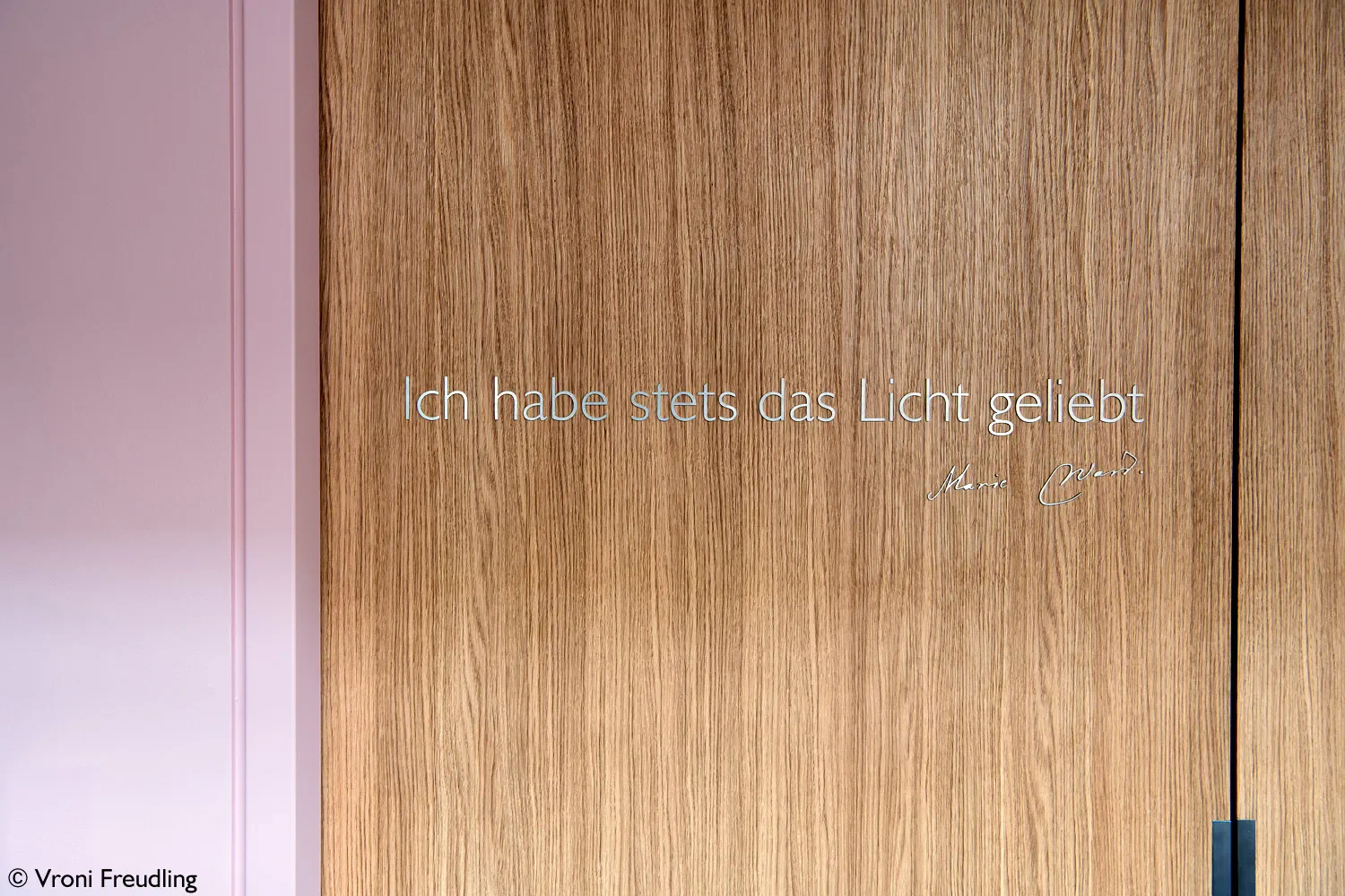 Holztür mit dem deutschen Zitat 'Ich habe stets das Licht geliebt' von Marie Curie