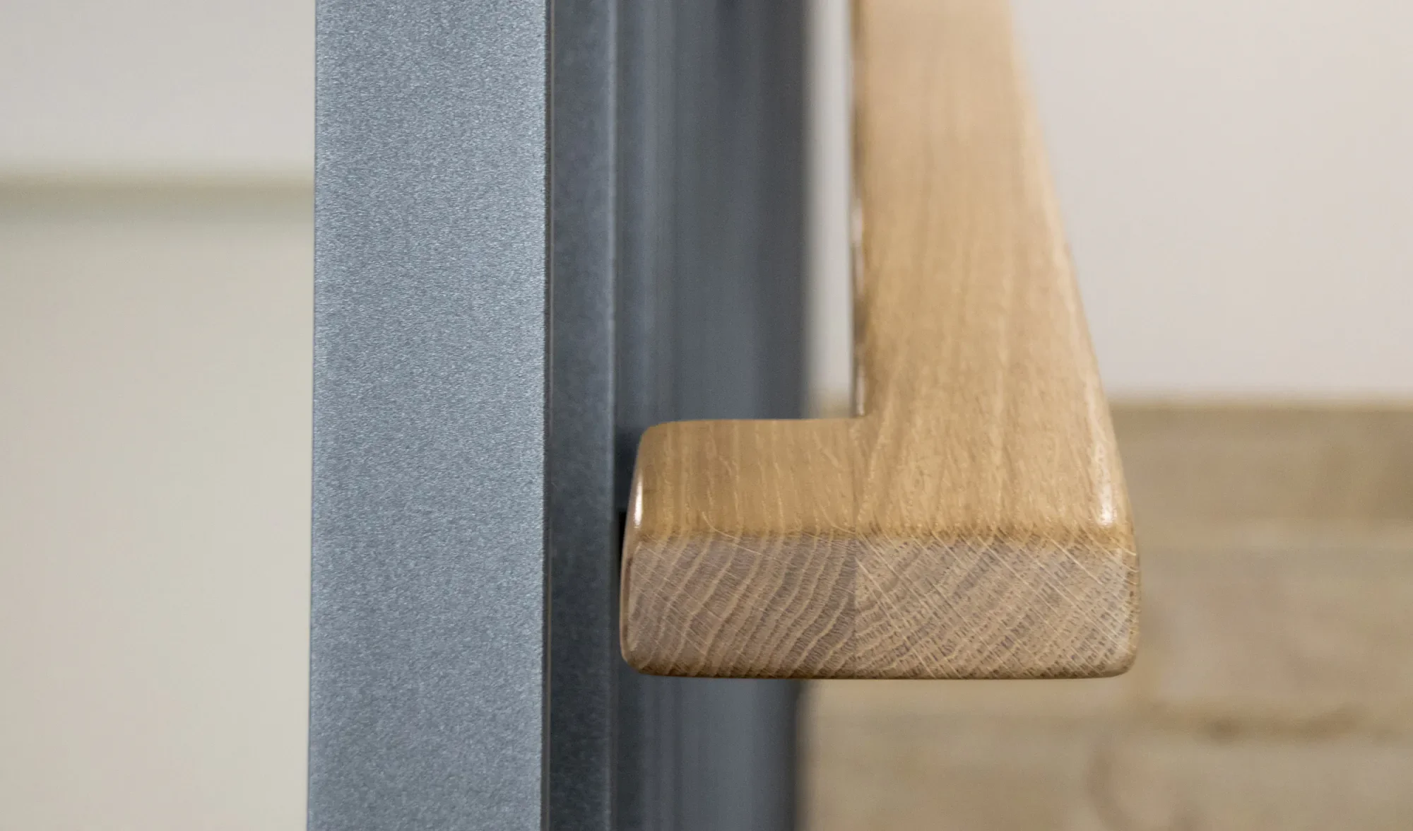 Ein minimalistischer Holzstuhl steht auf einem Tisch aus schwarzem Material, gegen eine beige Wand.