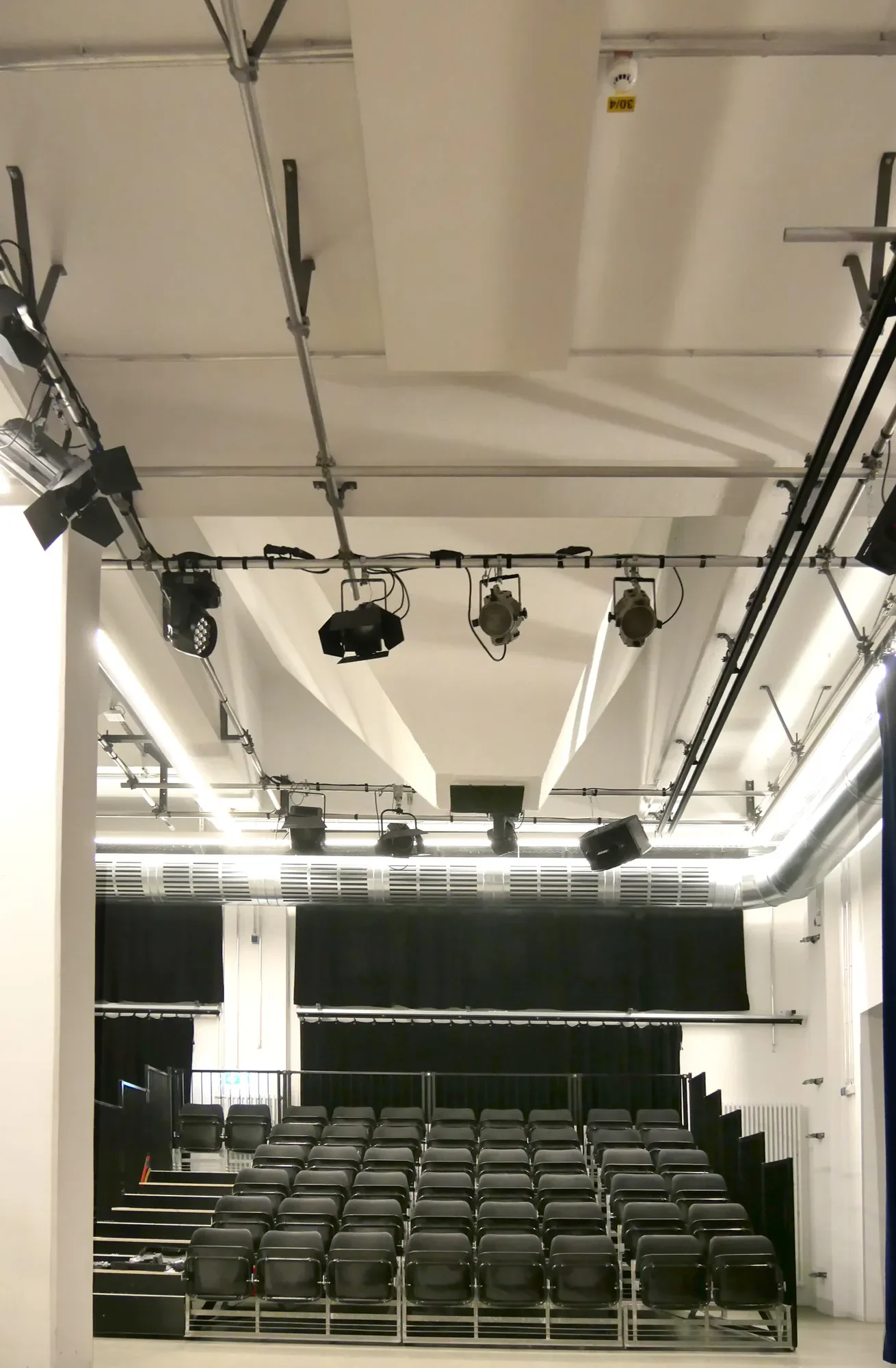Leeres Theater mit Sitzreihen und Beleuchtungsausrüstung an der Decke.