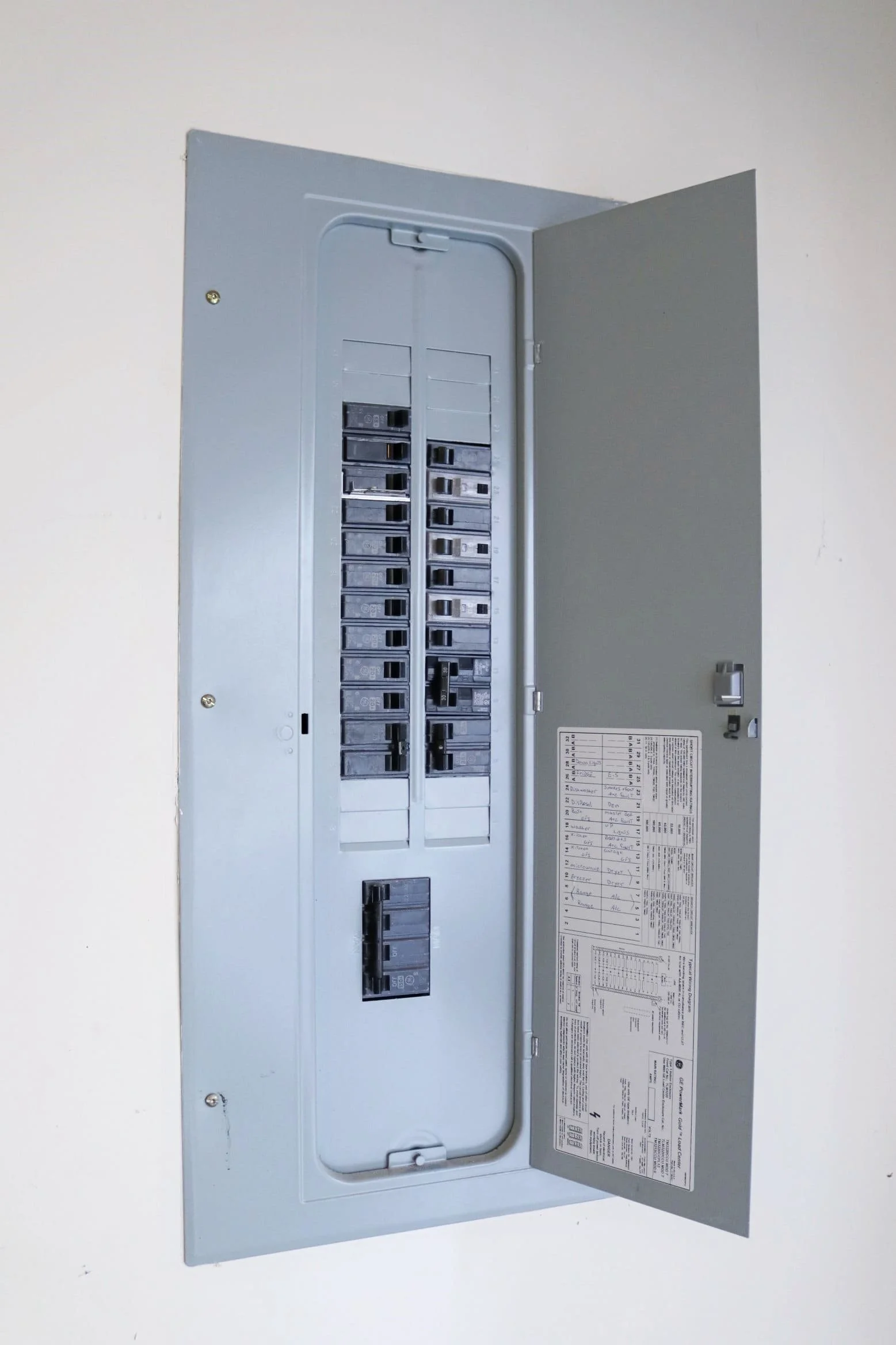 Electrical breaker panel with its door open, showing circuit breakers inside.