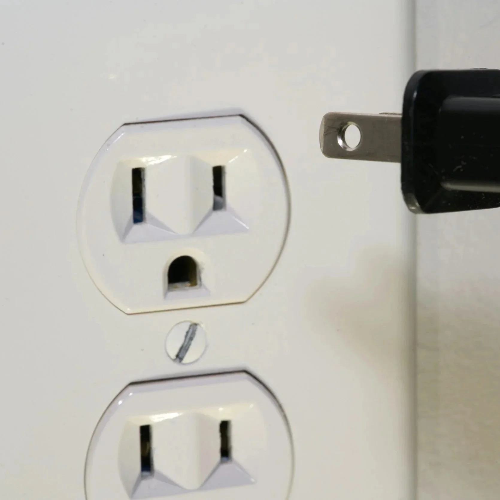 A technician inspects a residential electrical outlet with a digital multimeter to diagnose power failure issues in a darkened room.