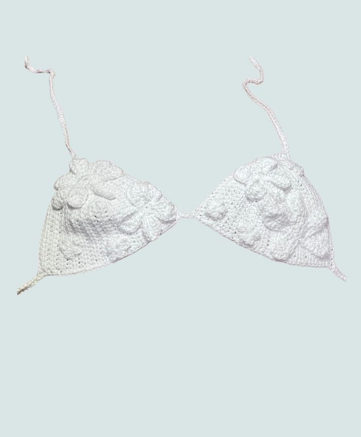 White crocheted bikini top with floral appliqué on light background.