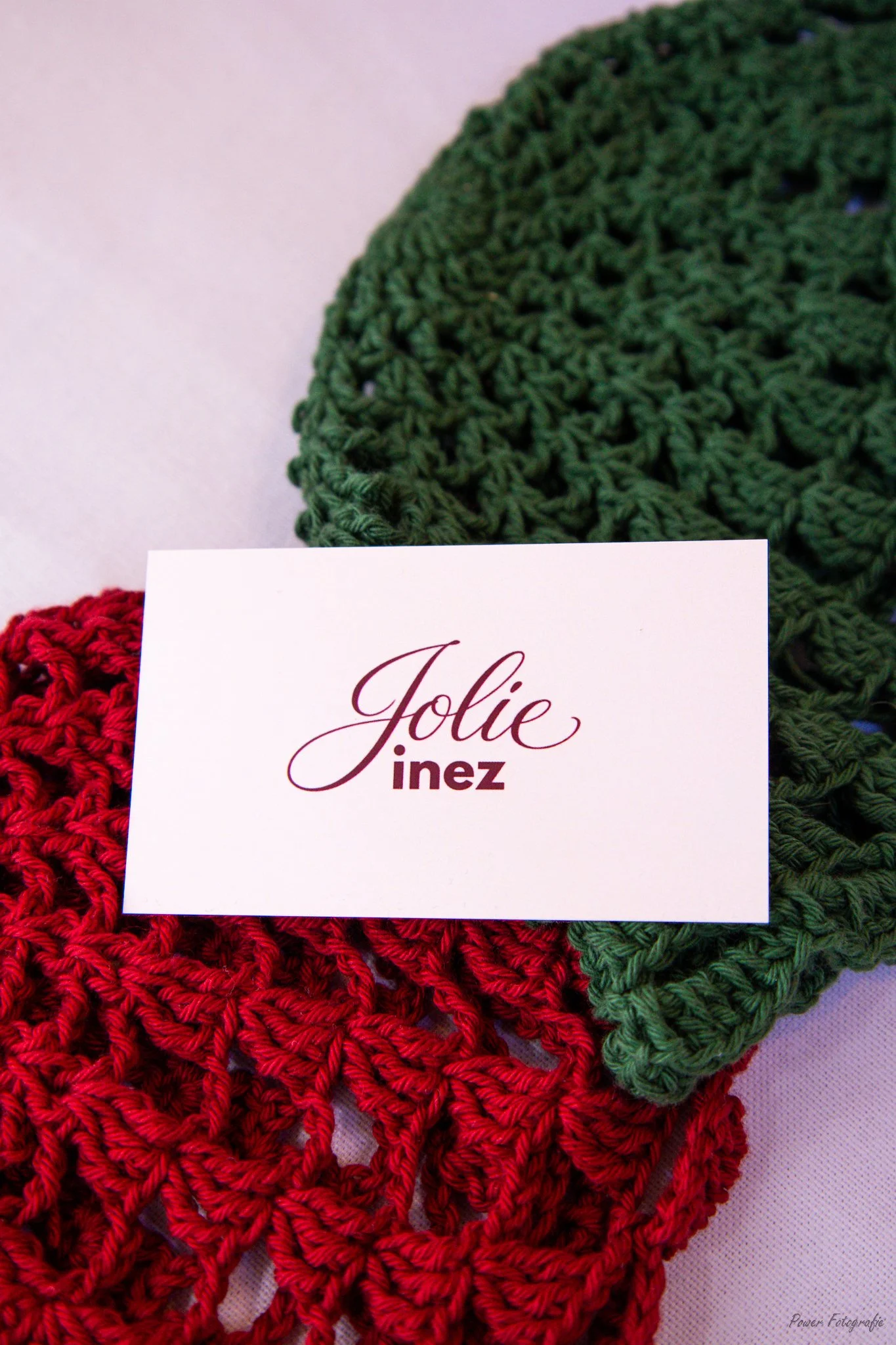 Red and green crocheted hearts with a white card that has the name 'Jolie Inez' written on it.