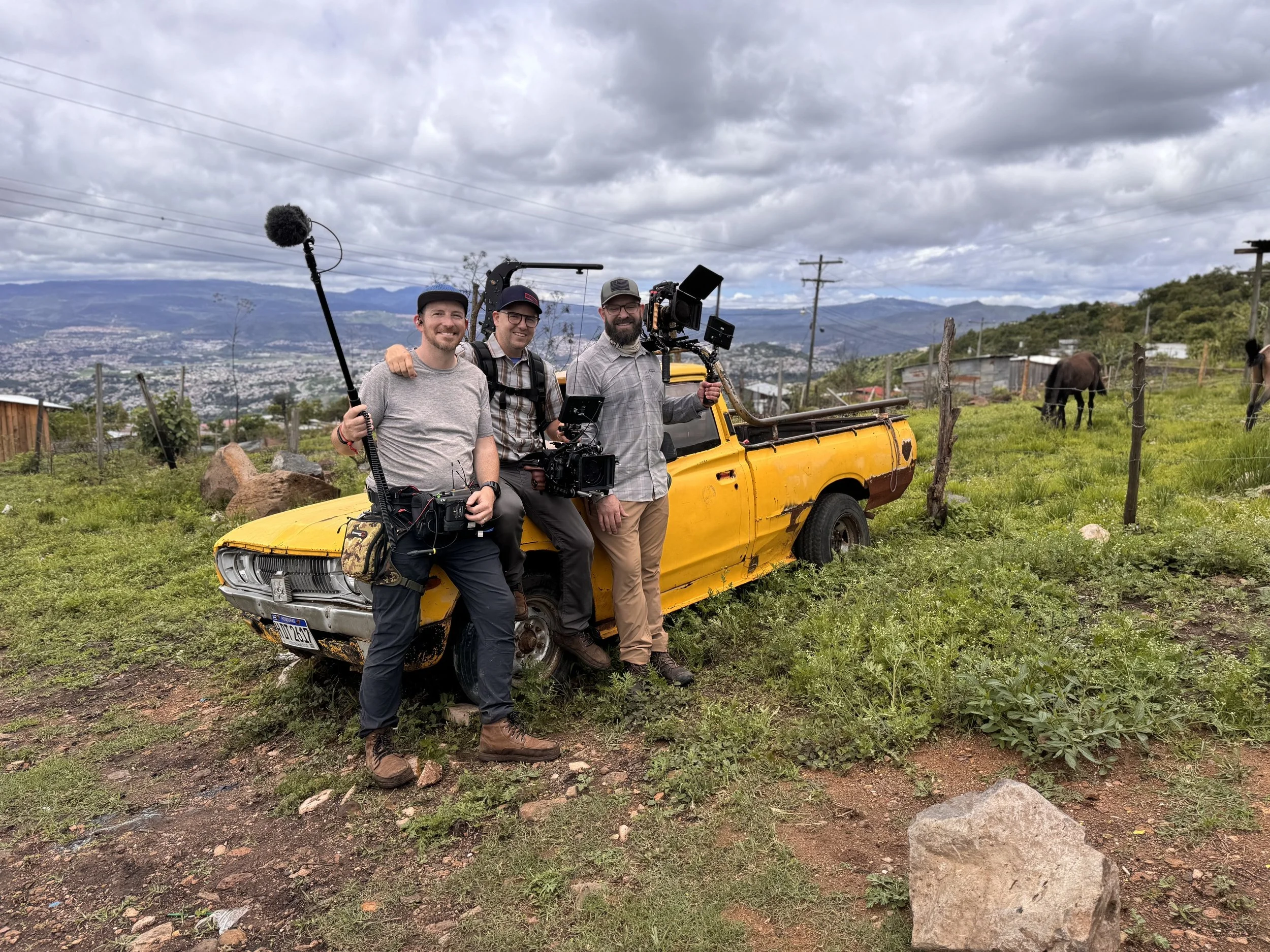 A video crew stands in front of a yellow truck.