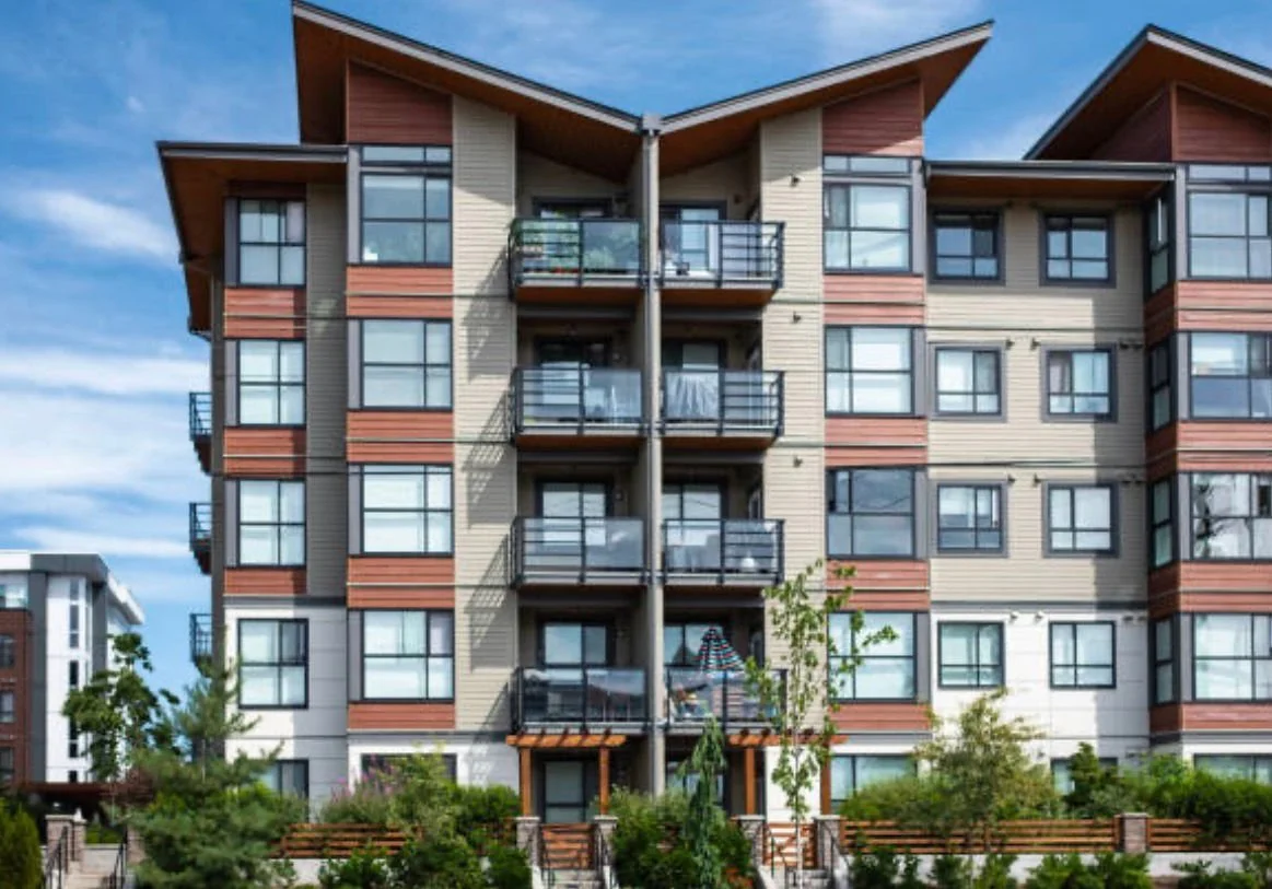 Multistory apartment building with balconies and a landscaped outdoor area.