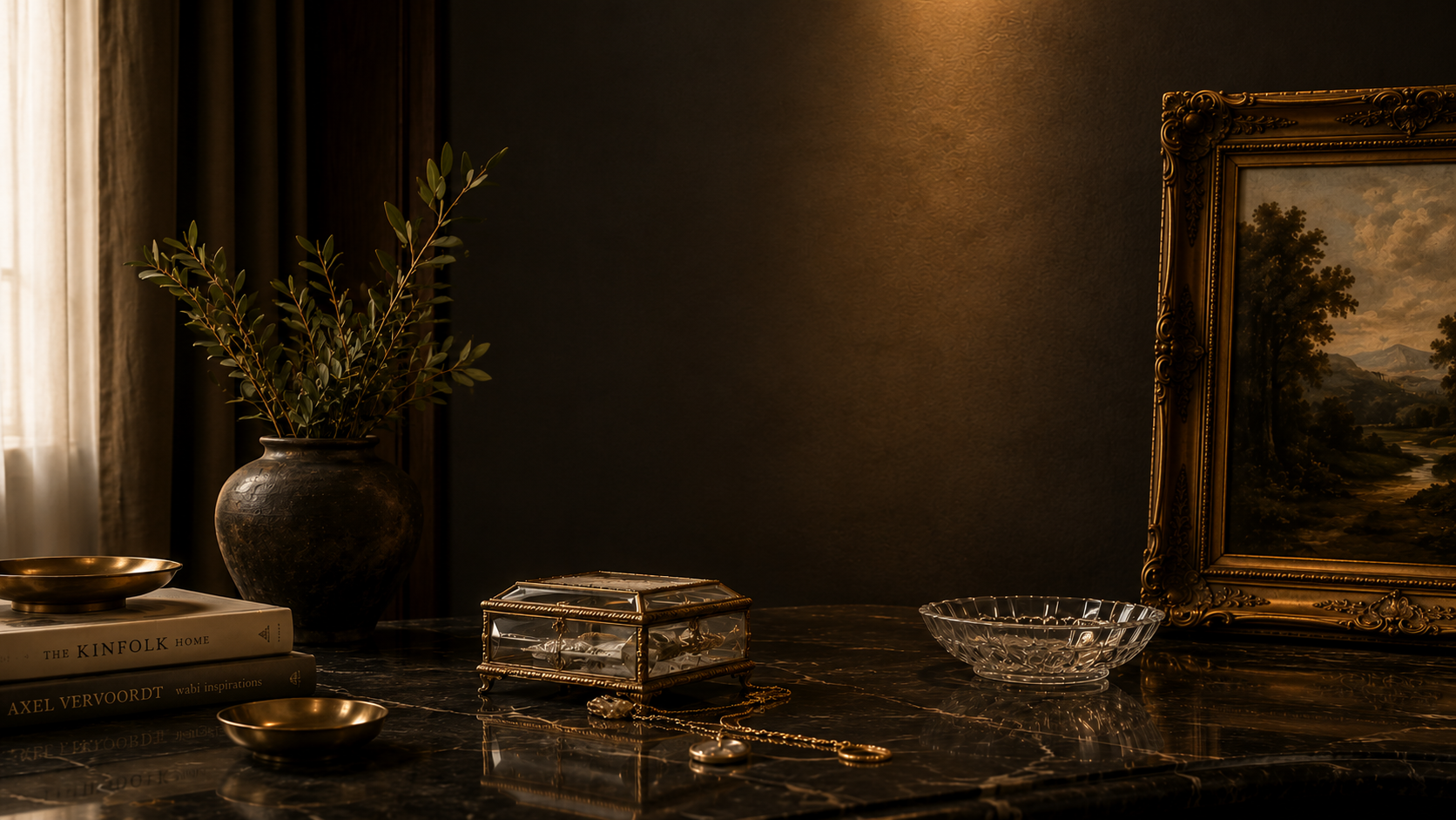 A dark interior scene featuring a marble tabletop with decorative items, including a ceramic vase with green foliage, a glass jewelry box, a glass bowl, a gold-colored dish, and necklaces. There's a framed landscape painting on the wall and a window with curtains on the left.