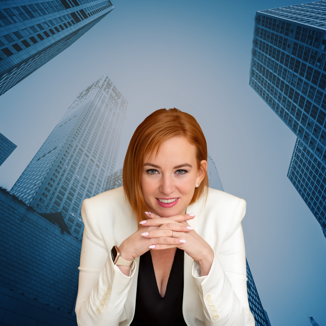 A woman with red hair, wearing a white blazer and black top, smiling at the camera with her hands under her chin, set against a backdrop of tall skyscrapers in a city.