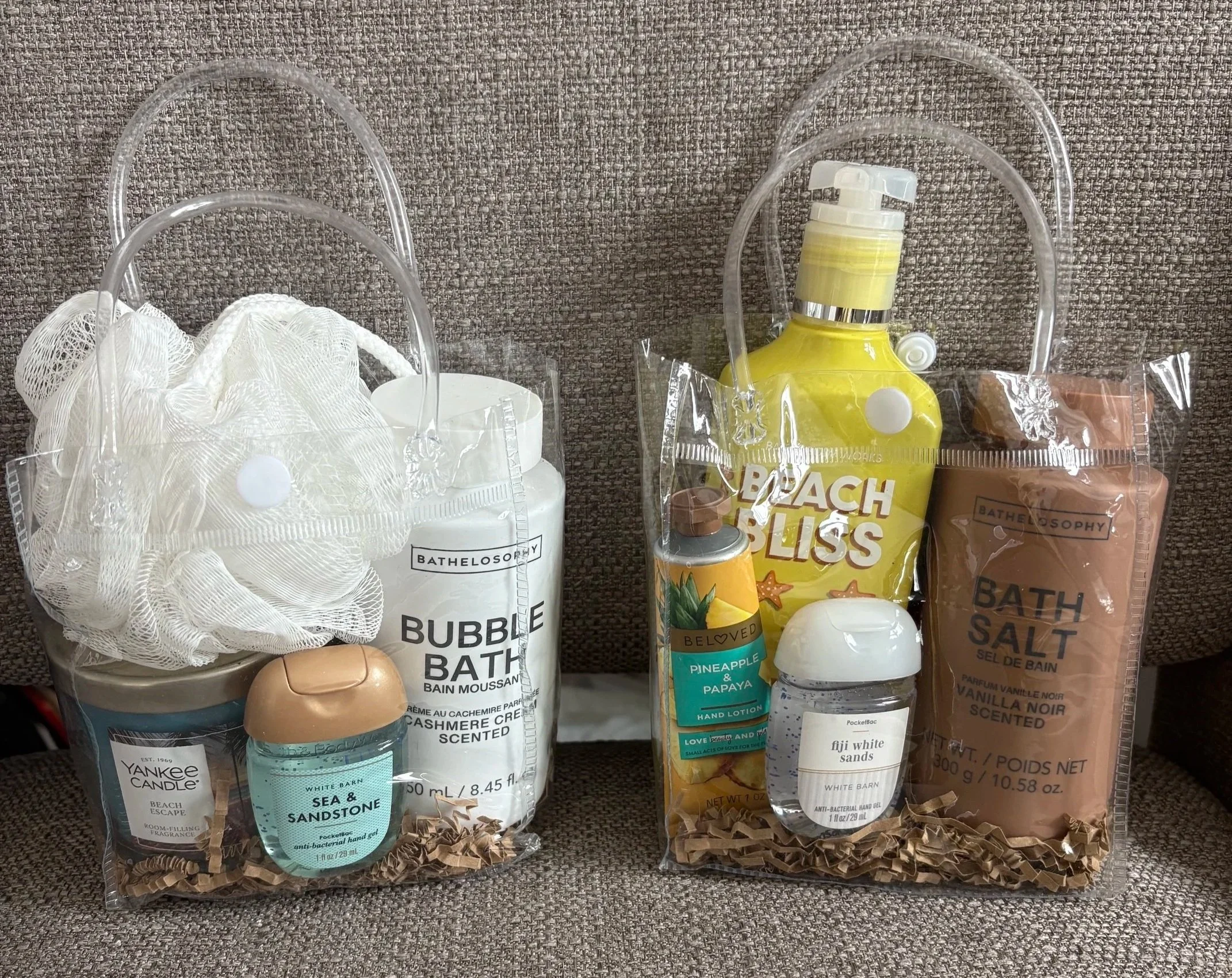 Various Bath & Body products including hand soap, lotion, bath salts, and candles arranged on a textured surface.