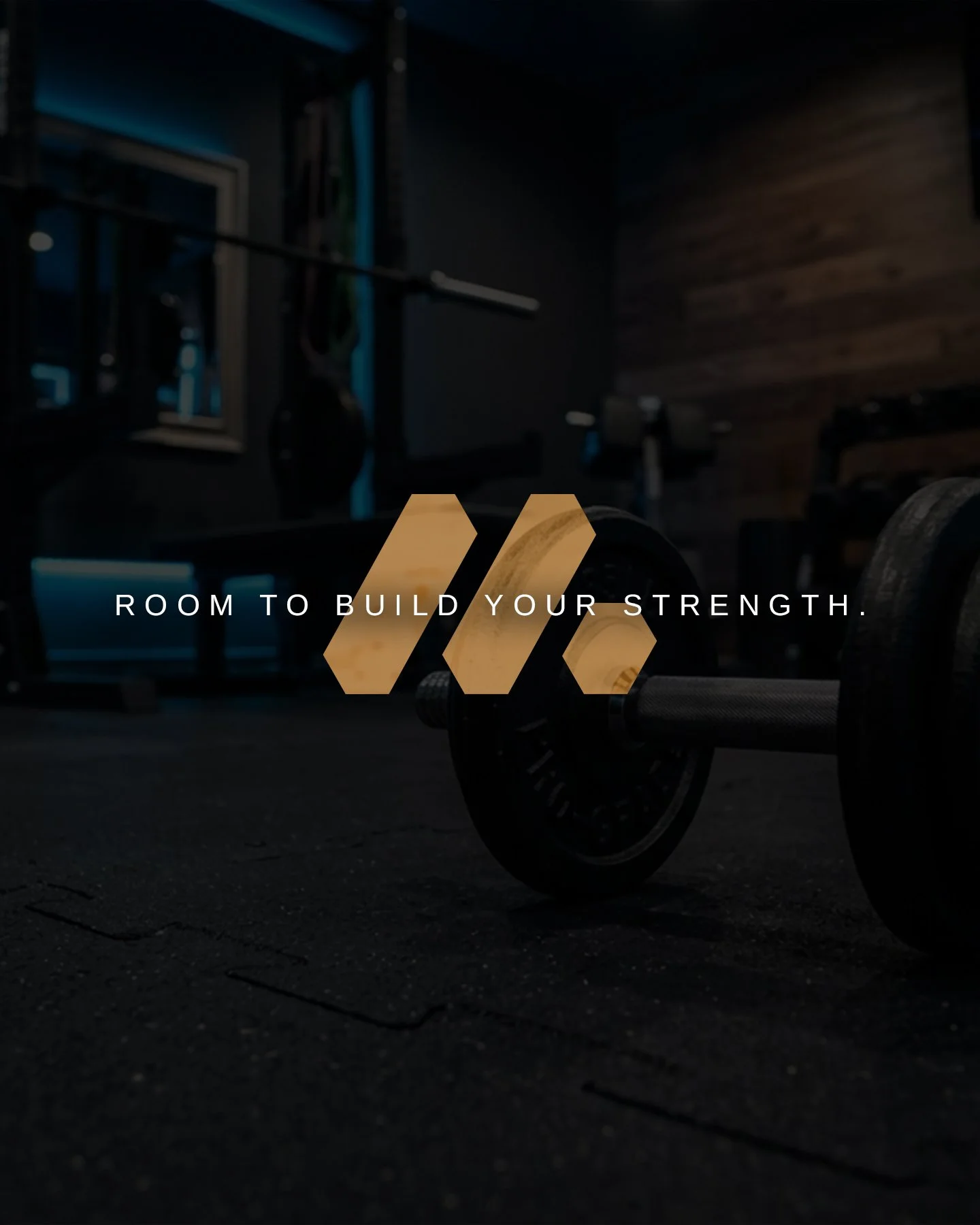 A skateboard lying on the floor in a dimly lit gym with gym equipment in the background and the text 'Room to build your strength.'