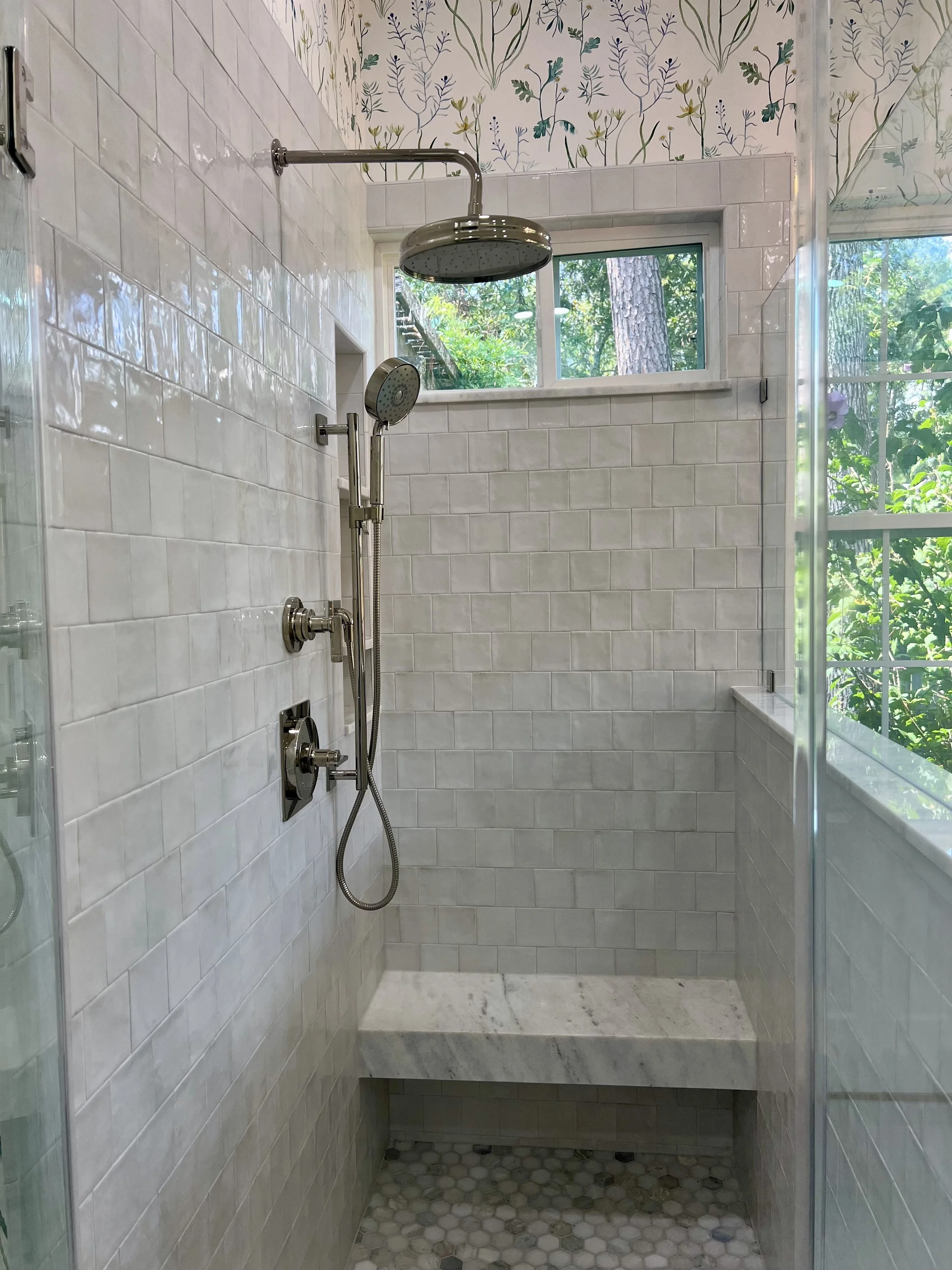 Shower area with white subway tiles, a window showing greenery outside, overhead rain shower head, and handheld shower fixture.