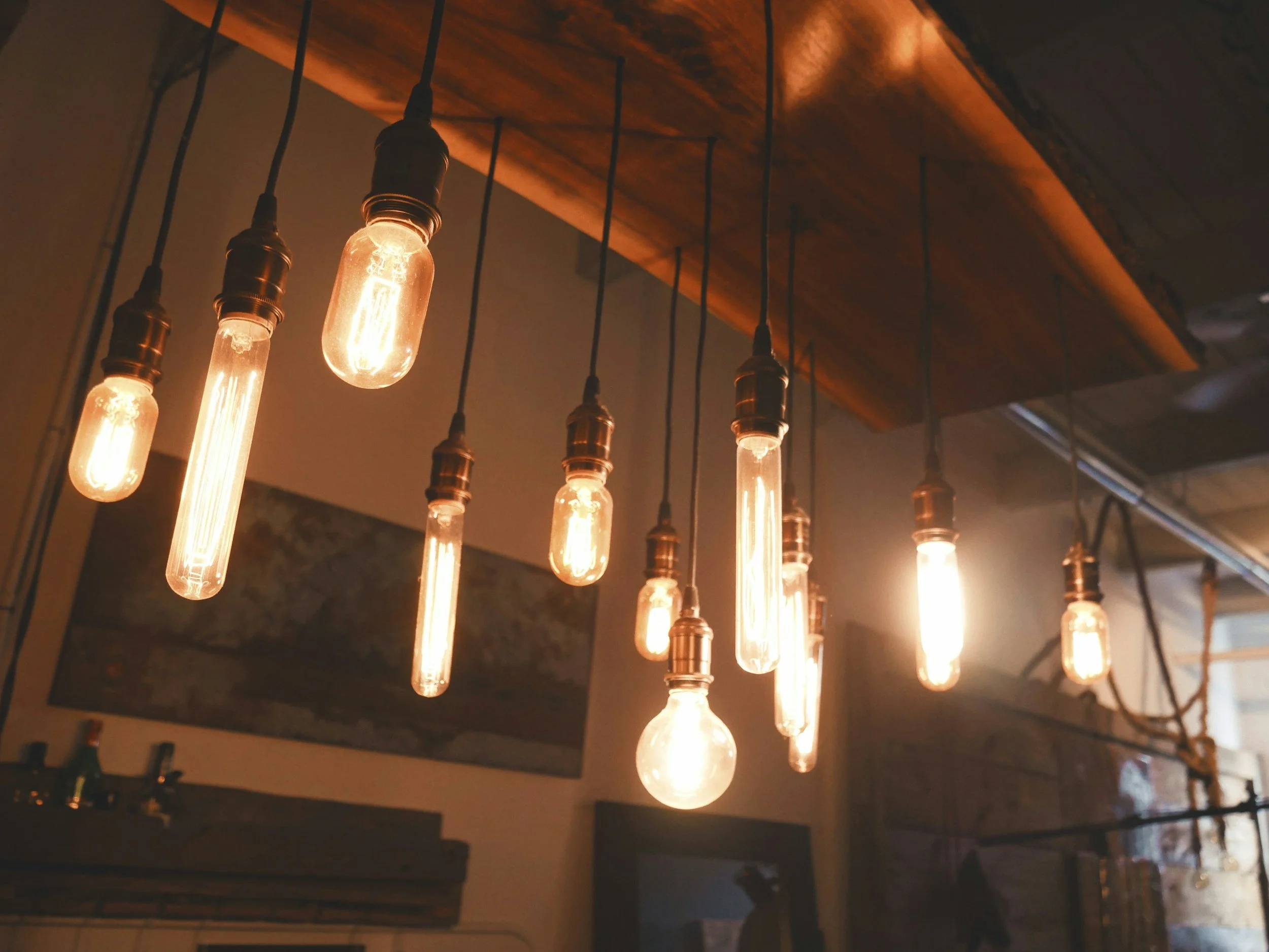 A row of vintage-style Edison light bulbs hanging from a wooden ceiling.