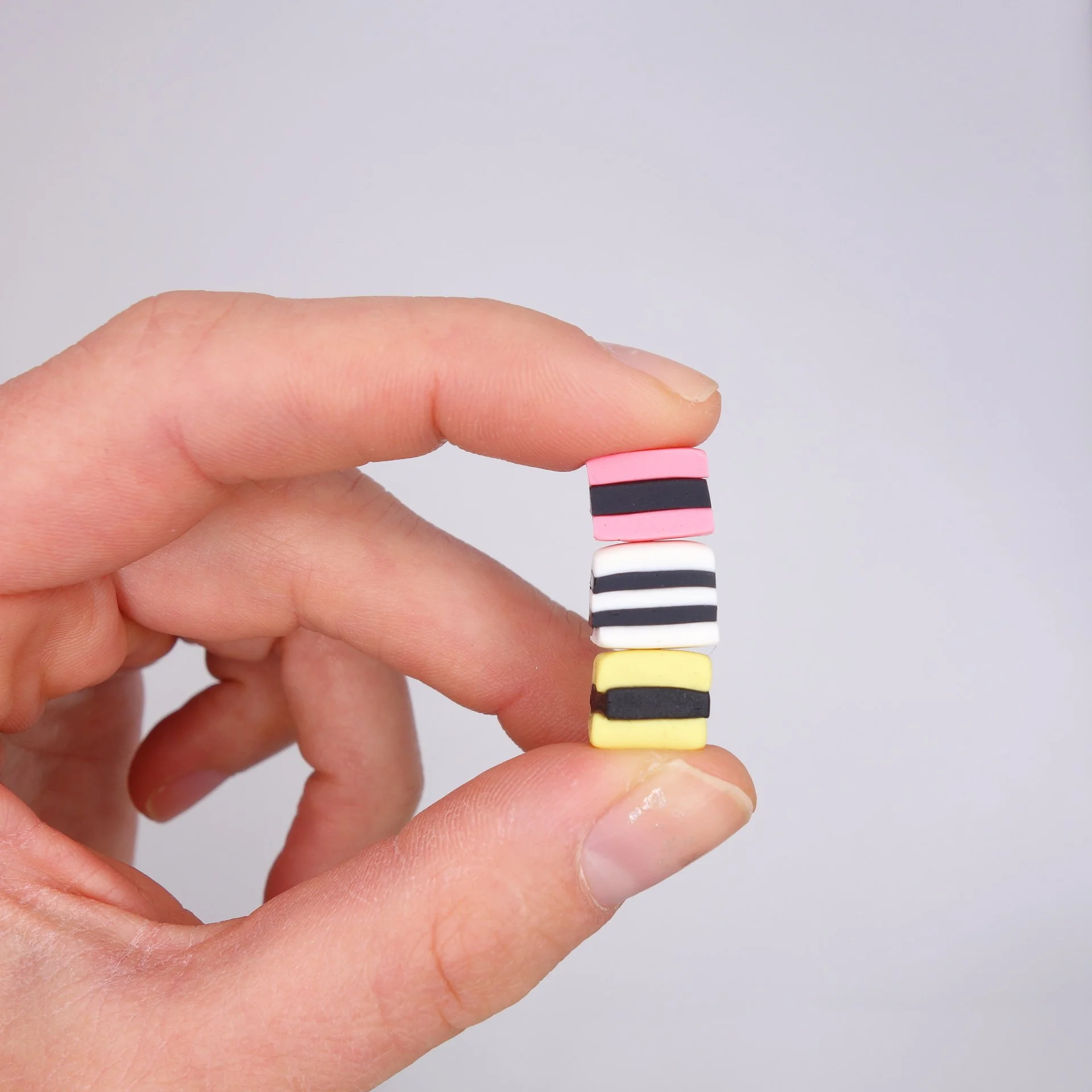 Nahaufnahme einer Hand, die bunte, gestapelte Spielzeugknöpfe hält, mit einem neutralen grauen Hintergrund.