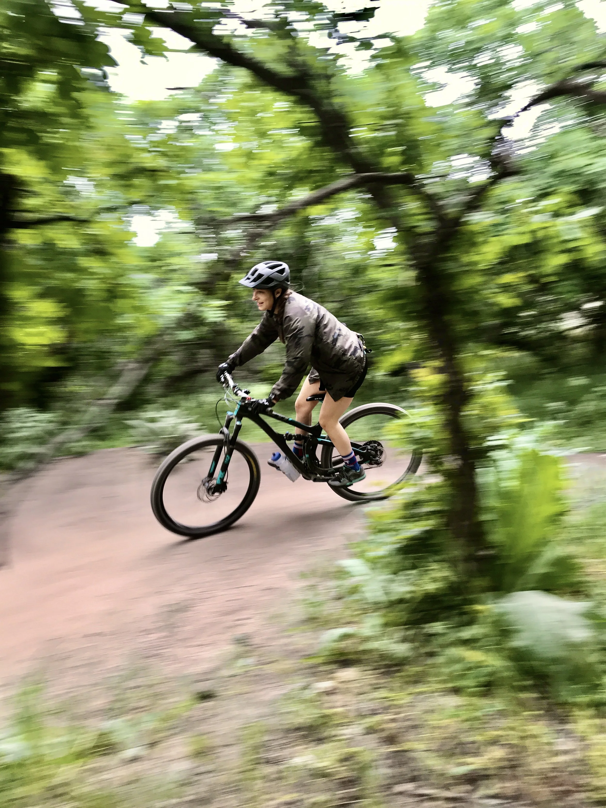 Mountain biking in the trees, smiling, laughing in the Rocky Mountains near Denver, Colorado.