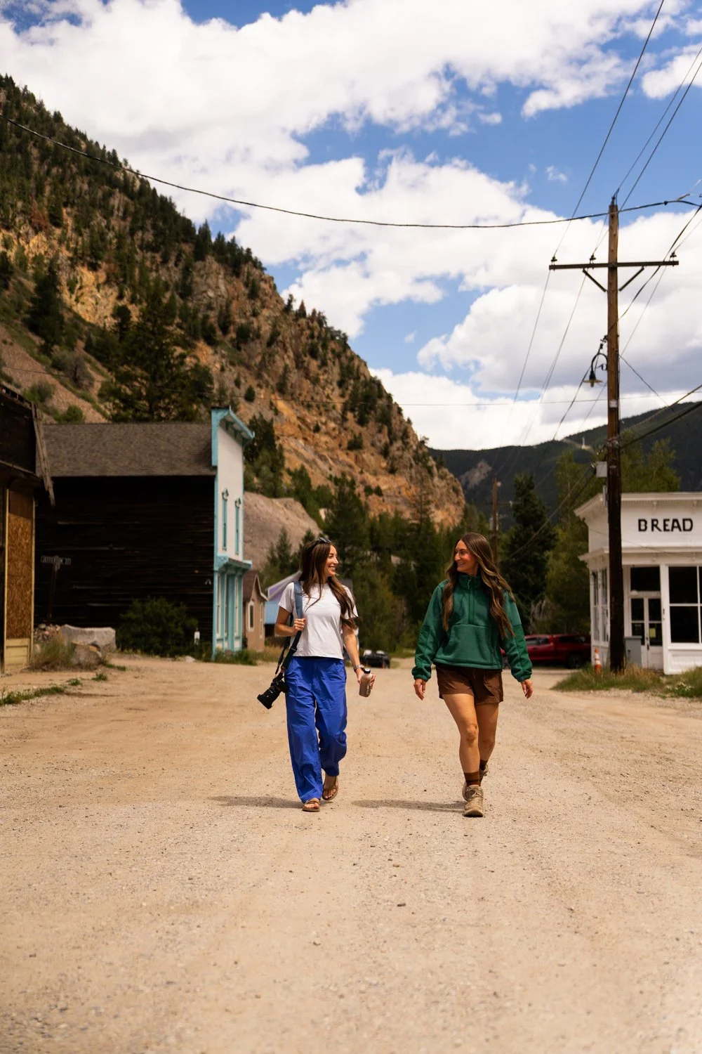Friends in a small mountain town, smiling and talking, with mountains and cloudy sky in the background in the Rocky Mountains, Colorado.