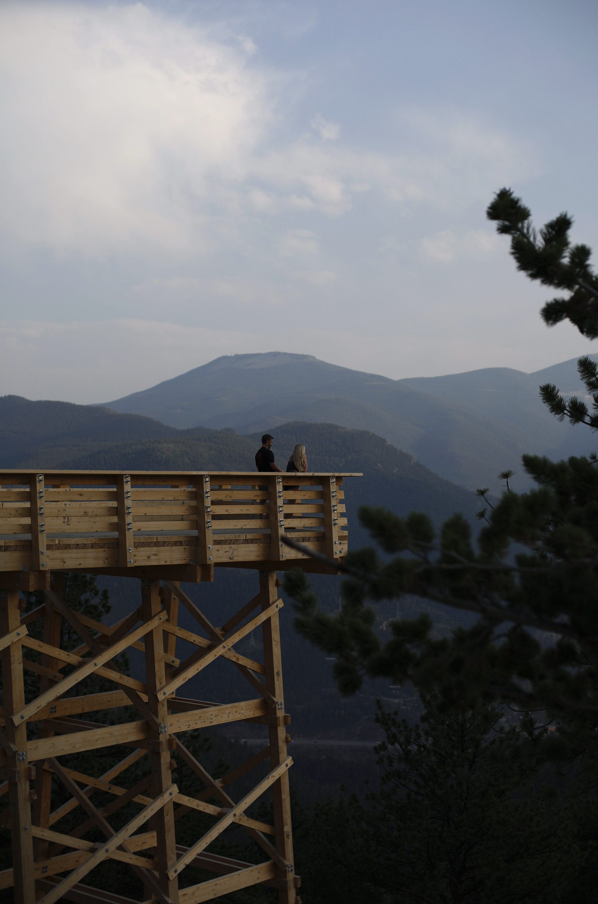 Friends and family on an observation deck overlooking mountain scenery with trees near Rocky Mountains, Colorado.