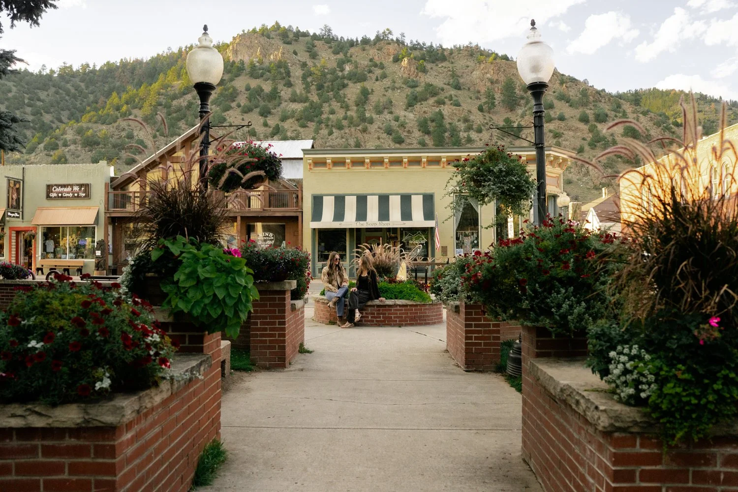 Friends talking in a small town square with flower planters, shops, and mountains near Denver, Colorado in the Rocky Mountains.