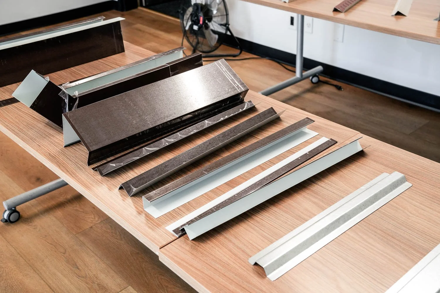 Various metal parts laid out on a wooden table in a showroom.