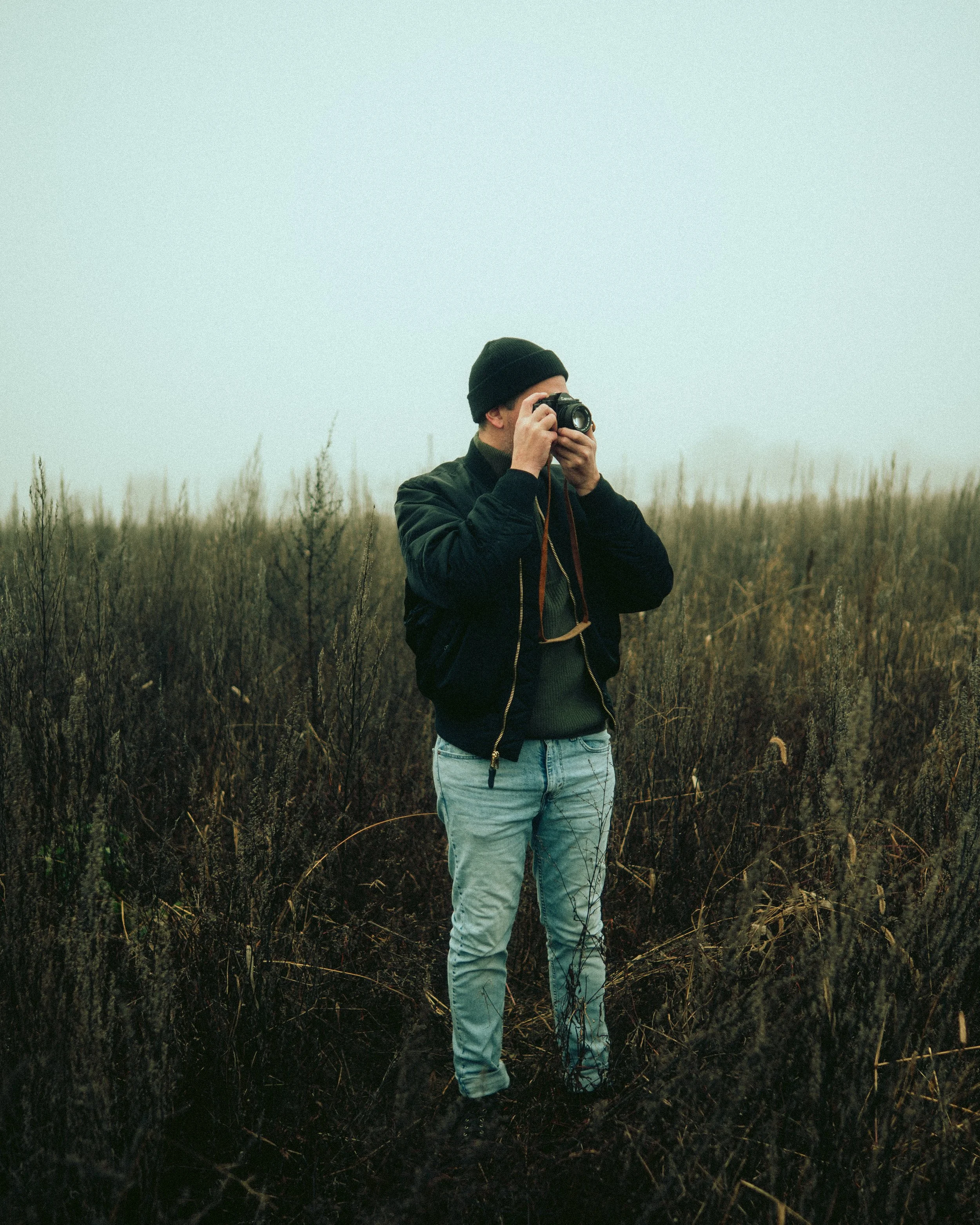 Mystisches Lifestyle-Portrait von Fotograf Julian Scherrmann auf einem Feld in Baden-Württemberg, der in eine Kamera schaut