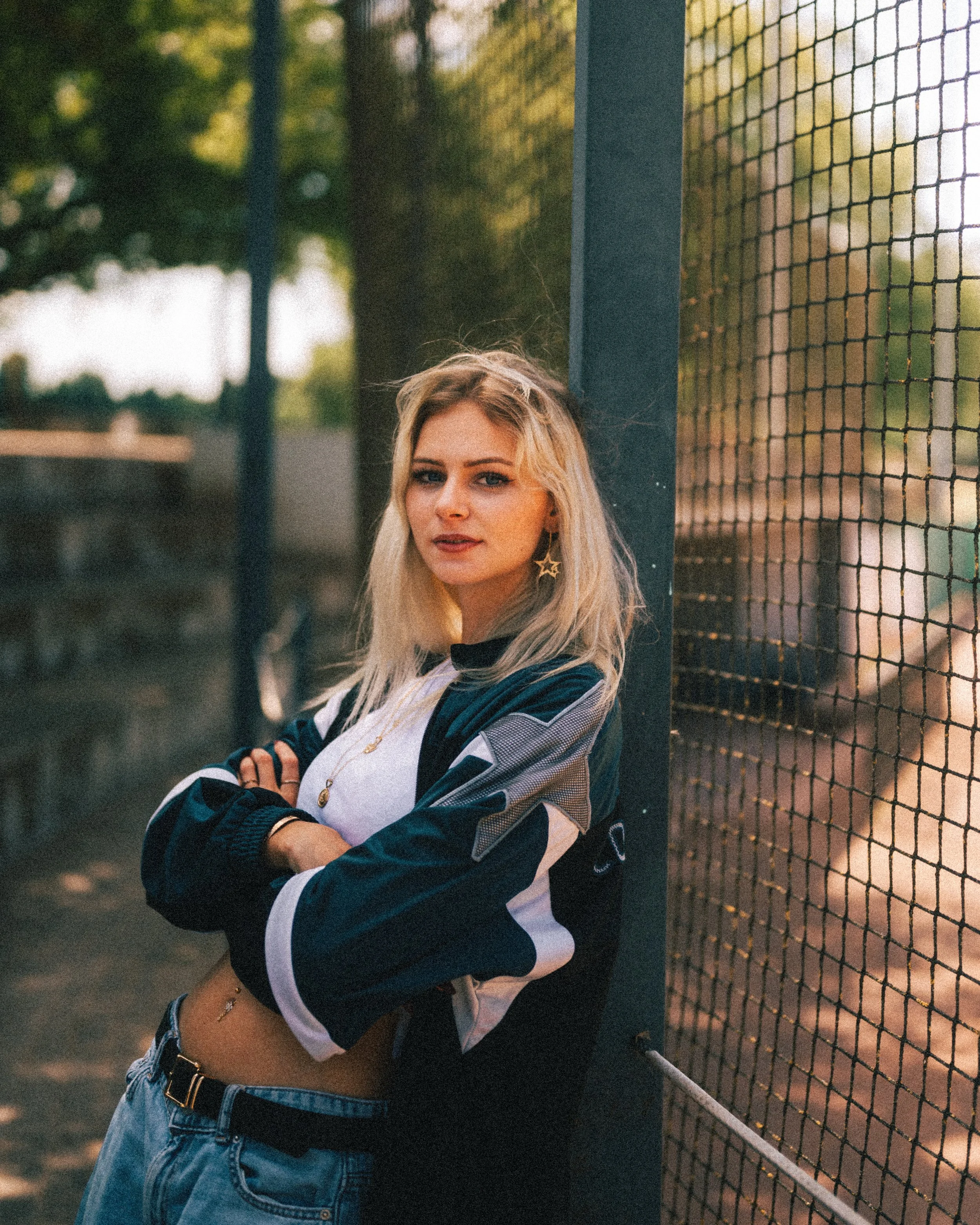 Sportliches Portrait von einer Frau, die an einem Geländer eines Sportfeldes lehnt