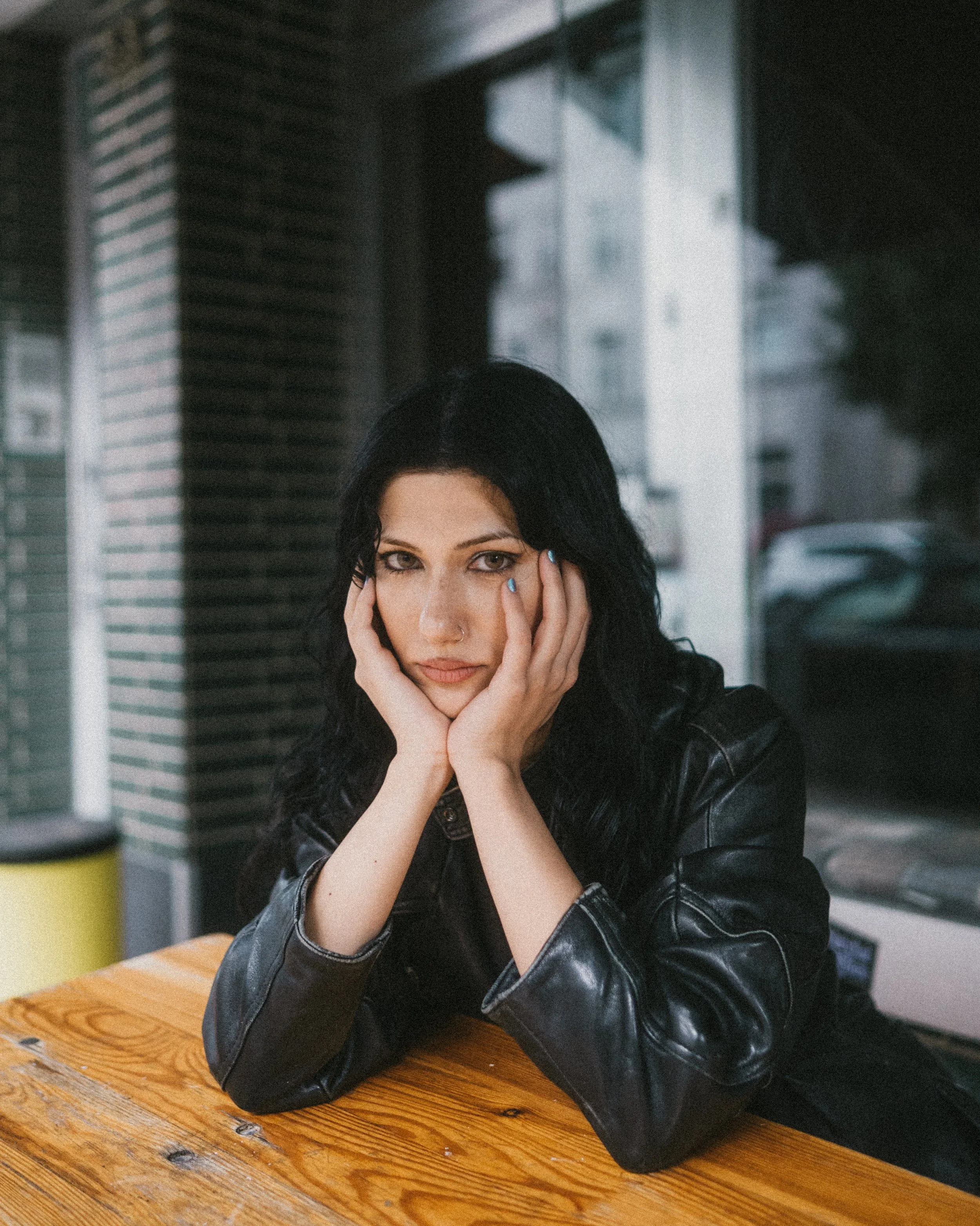 Portraitfotografie einer Frau, die an einem Holztisch vor einem Café im Kreuzviertel Dortmund sitzt