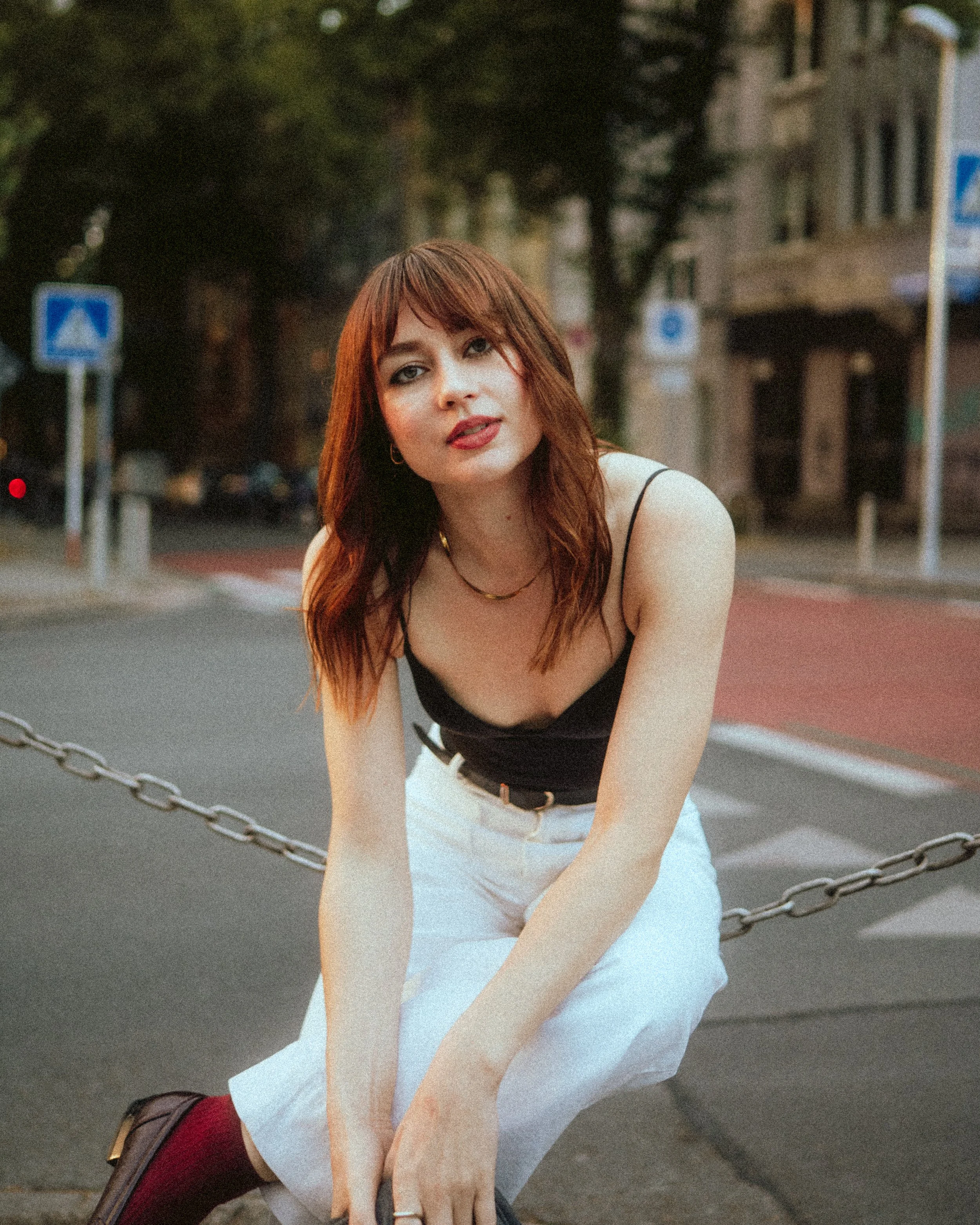 Eine editoriale Portraitfotografie einer Frau mit roten Haaren, die an einer Straße in Dortmund sitzt.