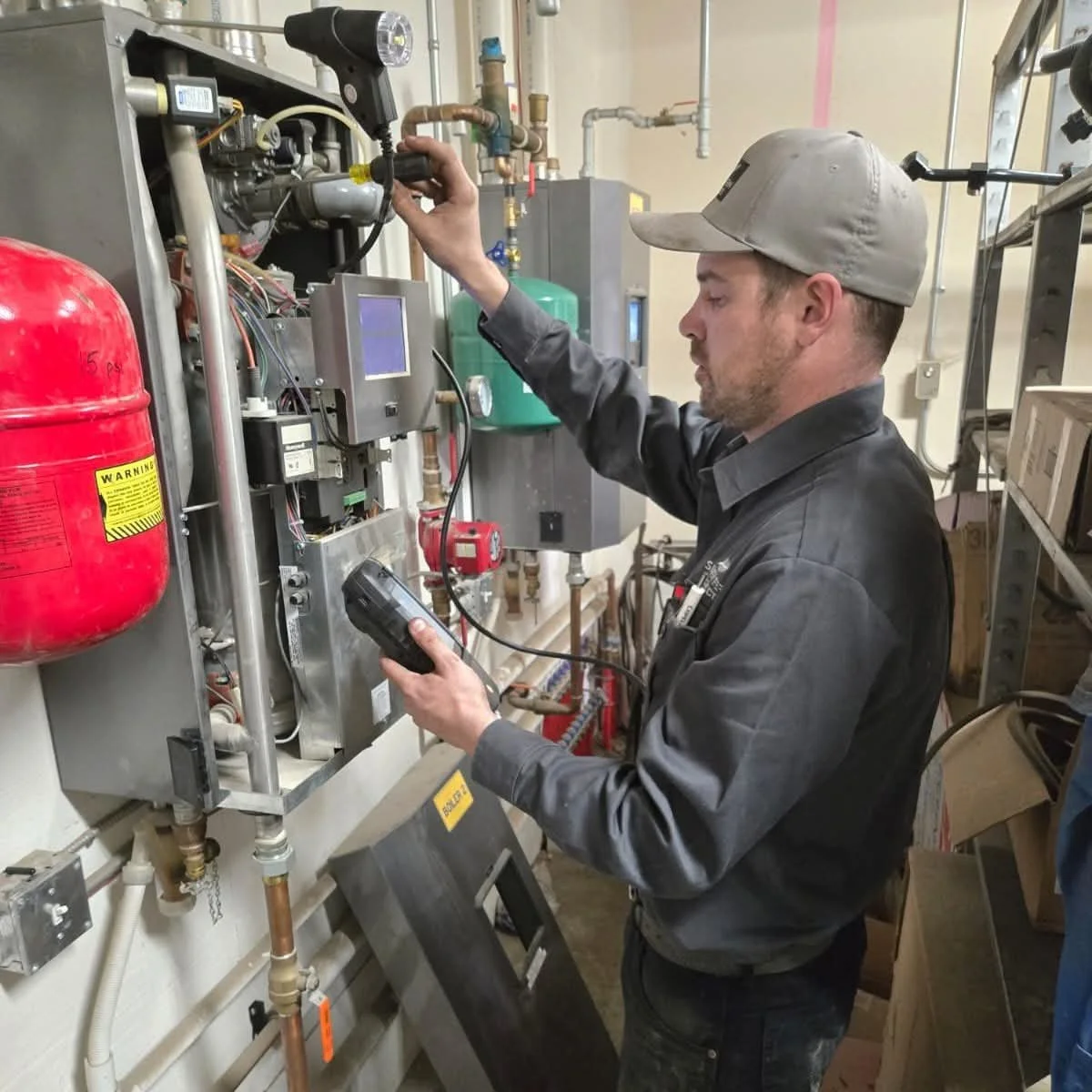A technician inspecting machinery with a handheld device in an industrial setting.