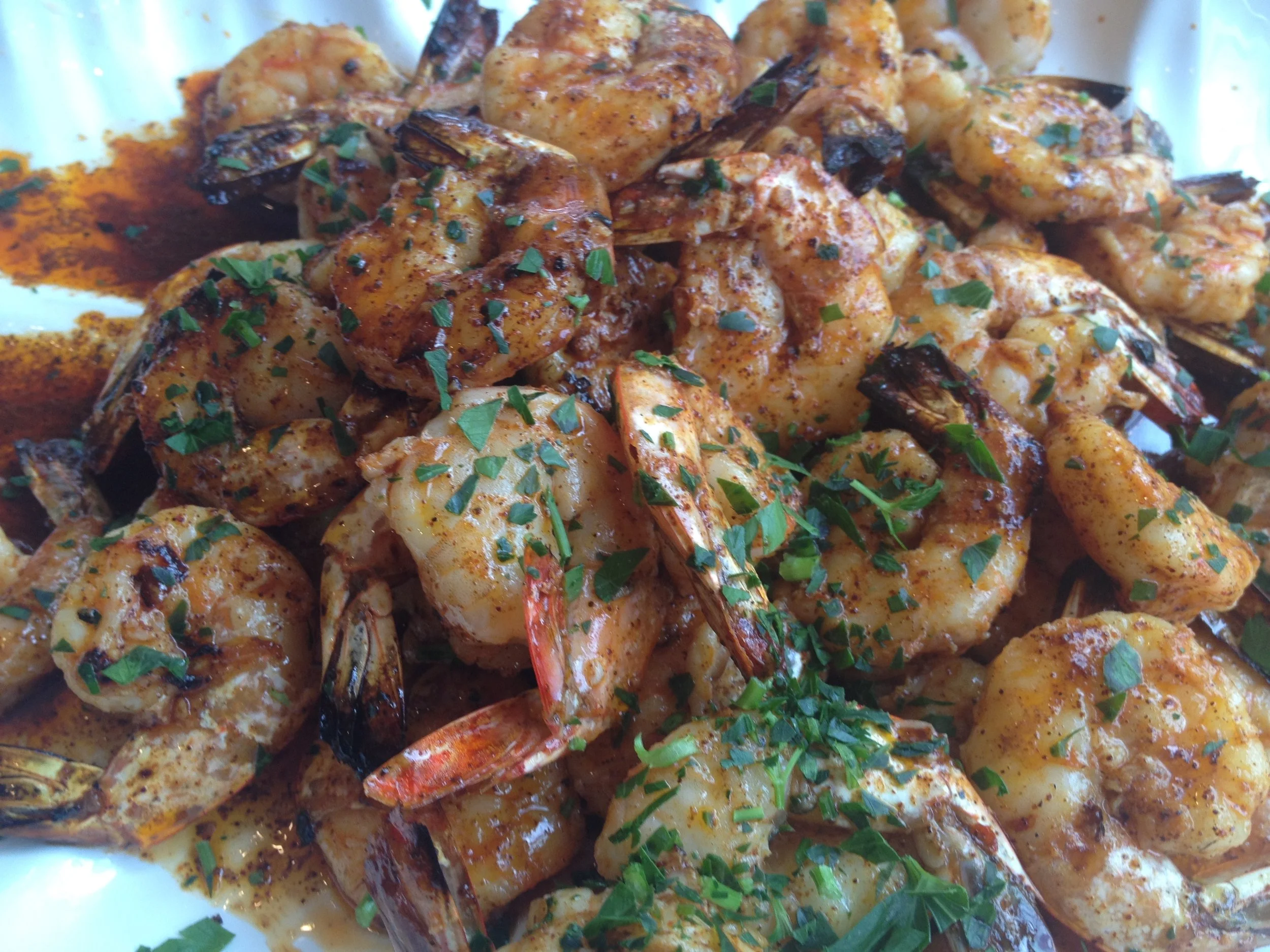 Close-up of cooked shrimp coated in a spicy sauce, garnished with chopped herbs.