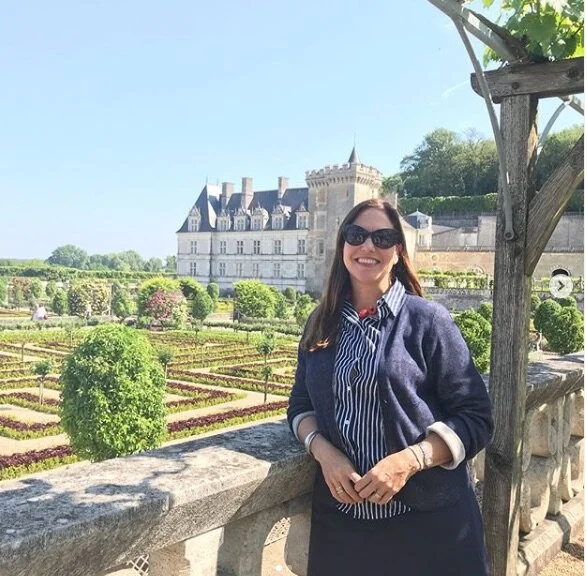 Woman smiling in front of a castle and vineyard at the Loire Valley in France.