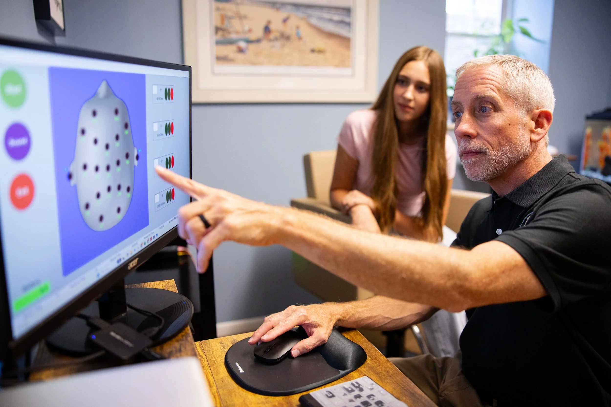 image of a male therapist pointing to a computer screen with a female client looking at the computer screen