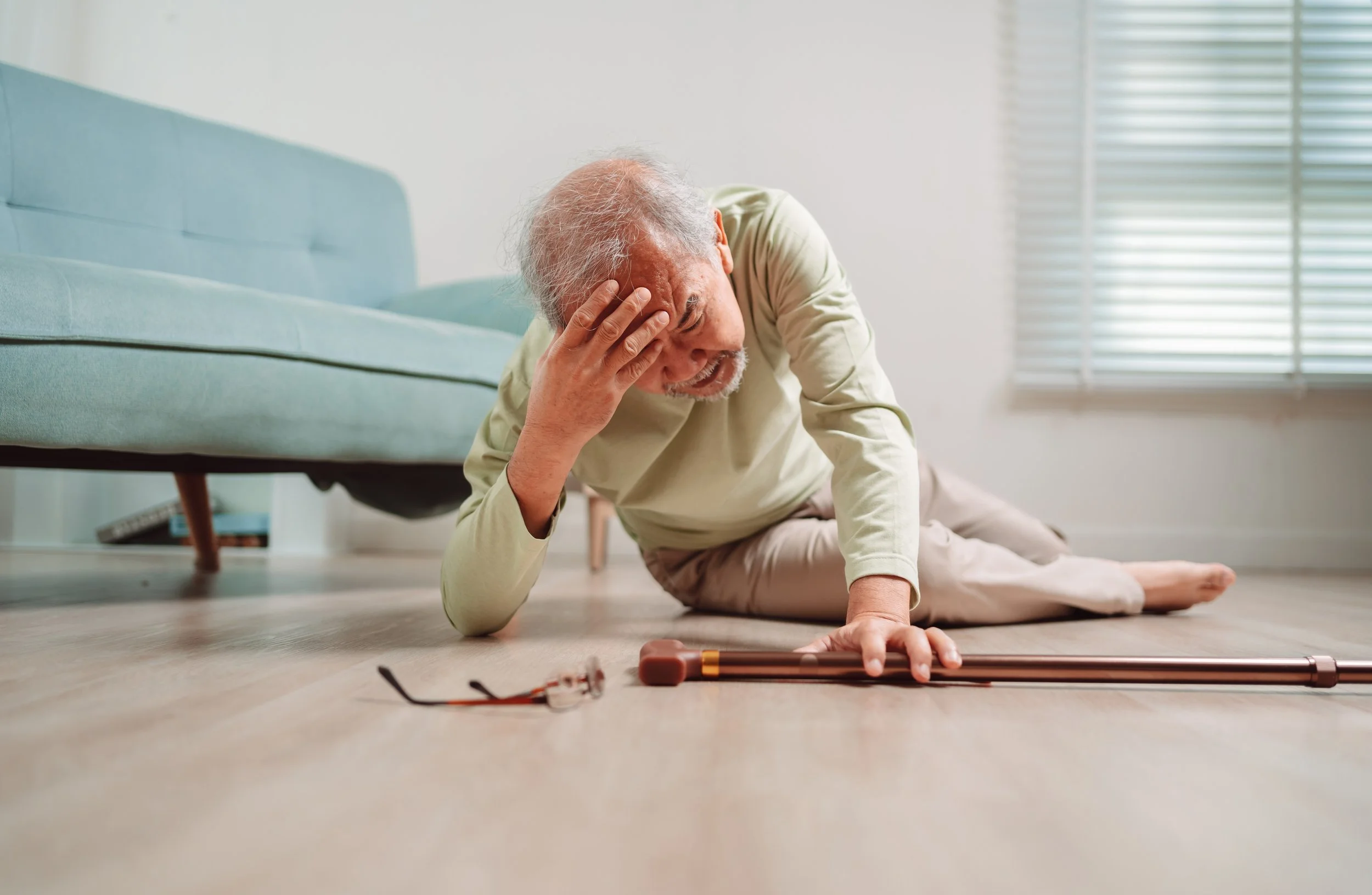 older man on the floor with his hand on his head