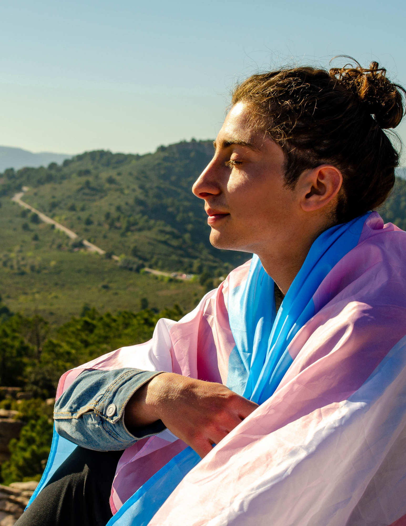 Adult practicing mindfulness outdoors to support emotional wellness and mental clarity in a transgender flag