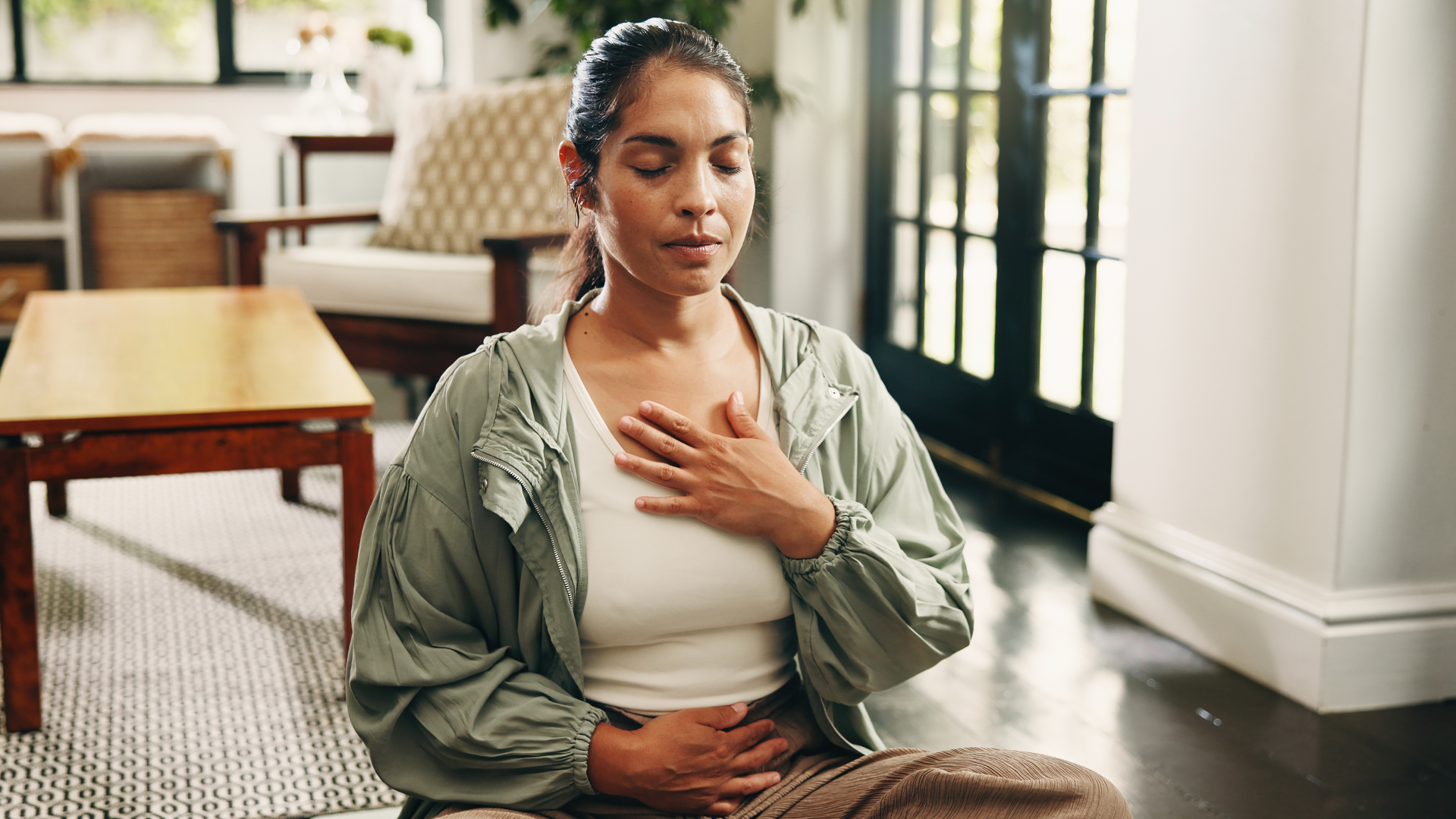 Image of women sitting on the floor in breathwork position with her eyes closed