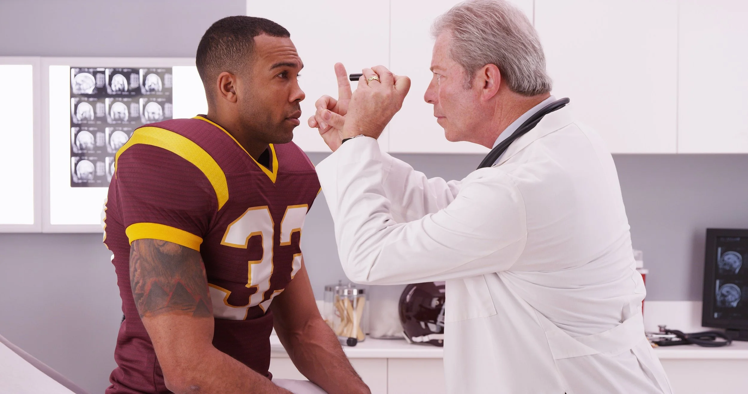 image of a football player at the doctors office getting his eyes checked for concussion