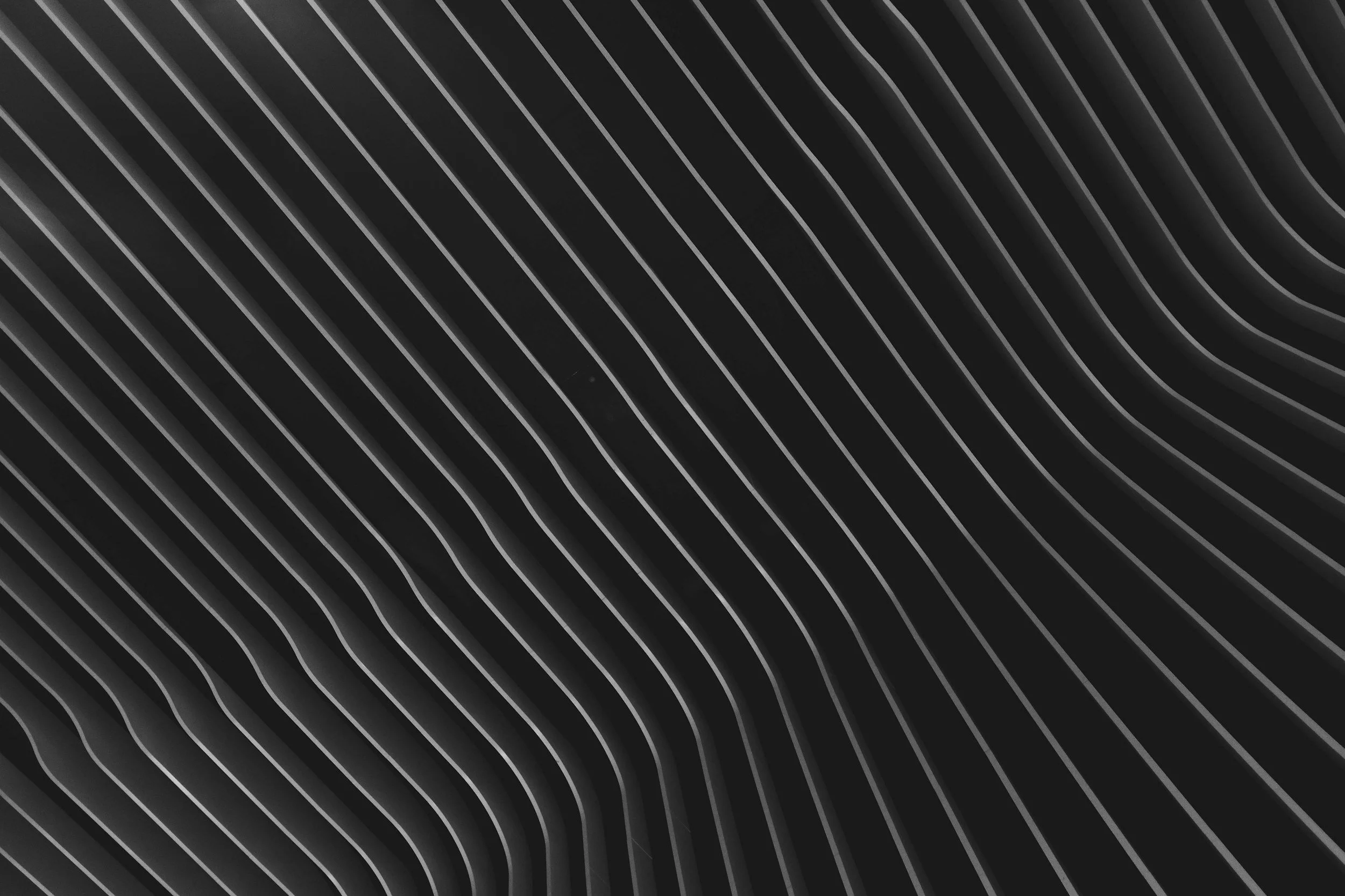 Black and white abstract background with diagonal striped lines that appear to be three-dimensional and geometrically patterned.